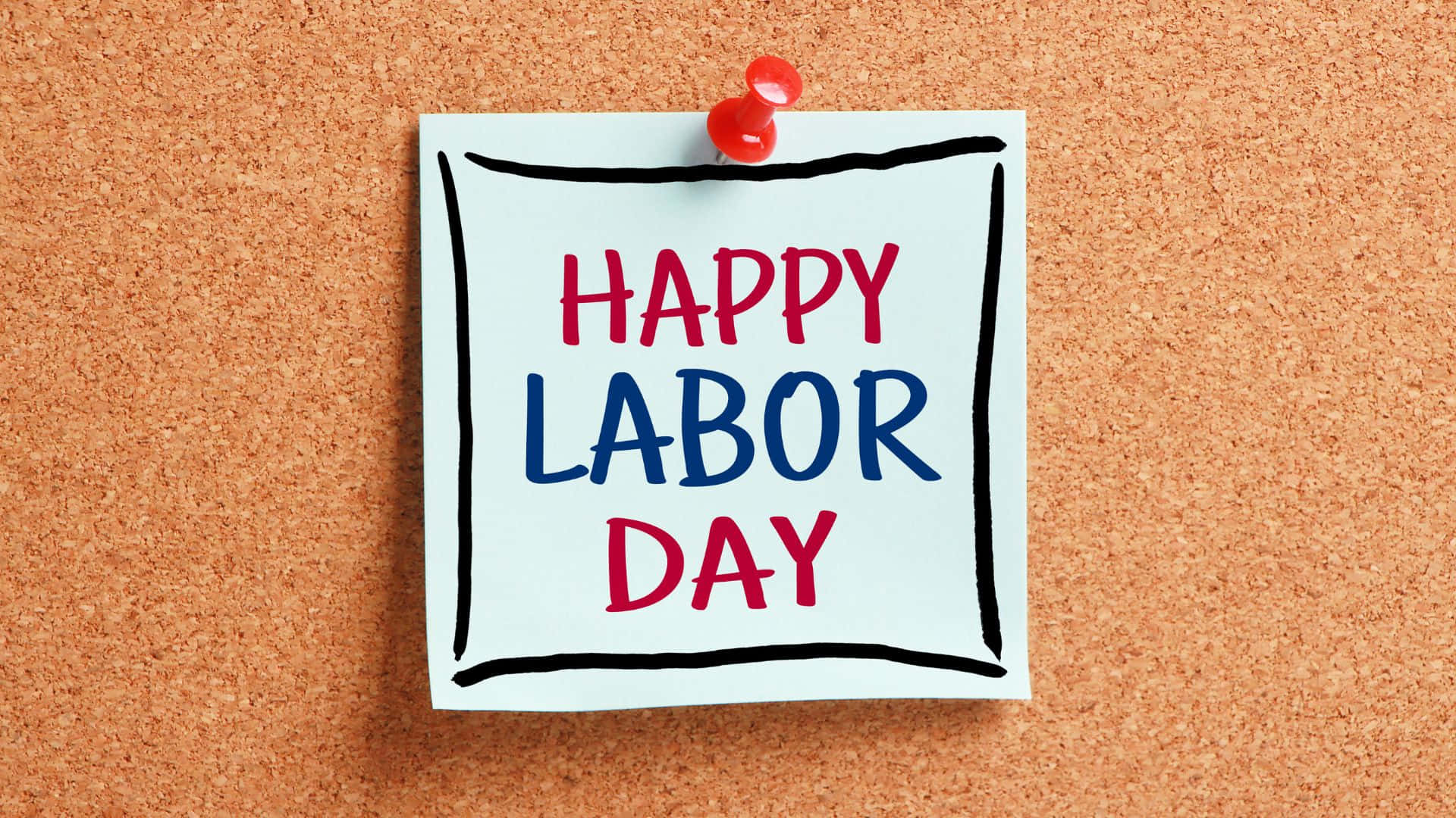勞動節 桌布 壁紙 — 一張白色便利貼，上面有紅色和藍色手寫字體 'HAPPY LABOR DAY'，用紅色圖釘釘在帶有紋理的軟木板上。