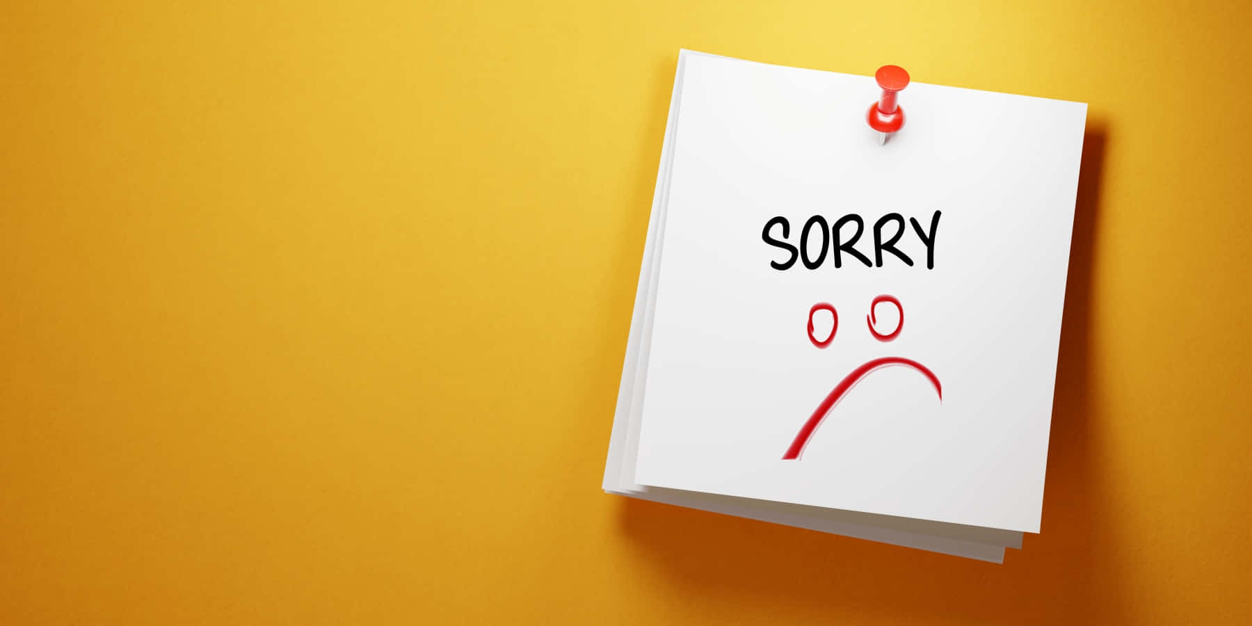 Post It 桌布 壁紙 — 一張白色便利貼釘在溫暖的黃色牆上，顯示「SORRY」字樣，上方有一個用圓圈和曲線繪製的簡單紅色悲傷臉孔。
