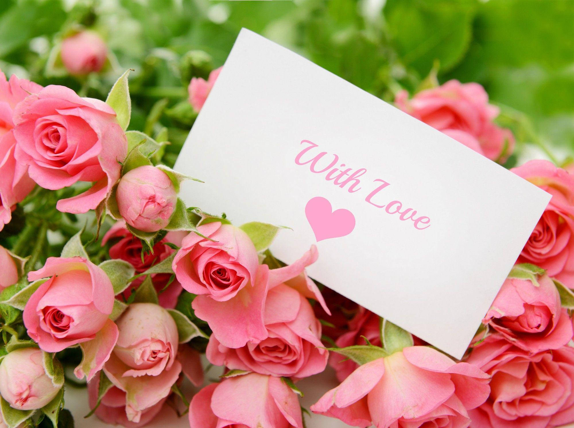 Pink Rose 桌布 壁紙 — 一張白色卡片，上面有粉紅色草書文字和心形，藏在鮮豔的粉紅玫瑰和綠葉之間。