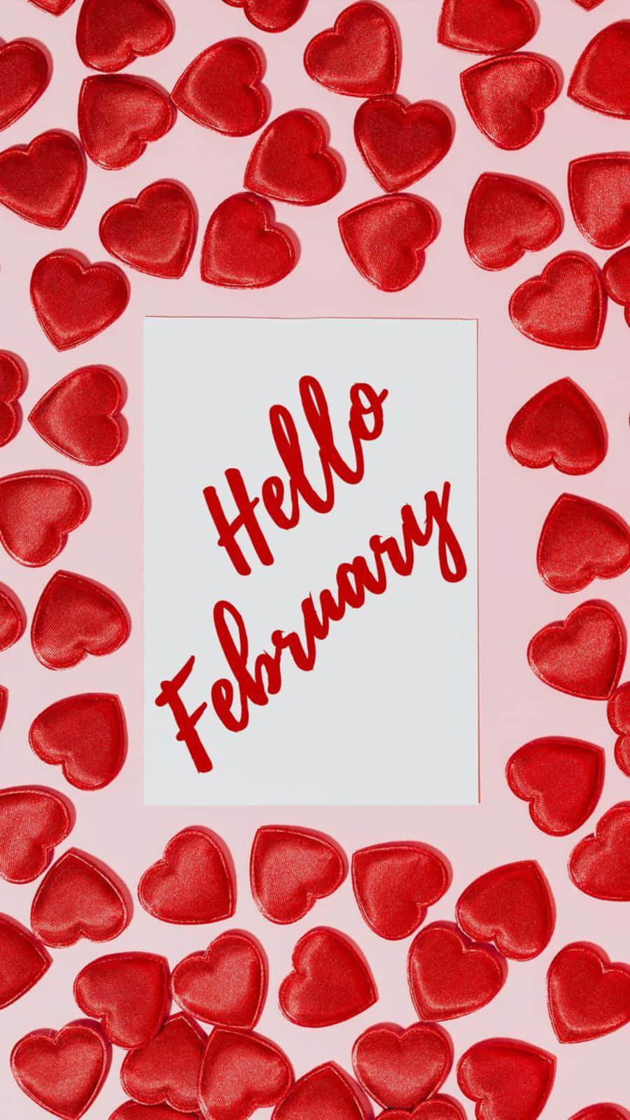 February iPhone 桌布 壁紙 — 一張白色卡片上以紅色草書寫著「你好二月」，周圍環繞著亮紅色心形，背景為柔和的粉紅色。