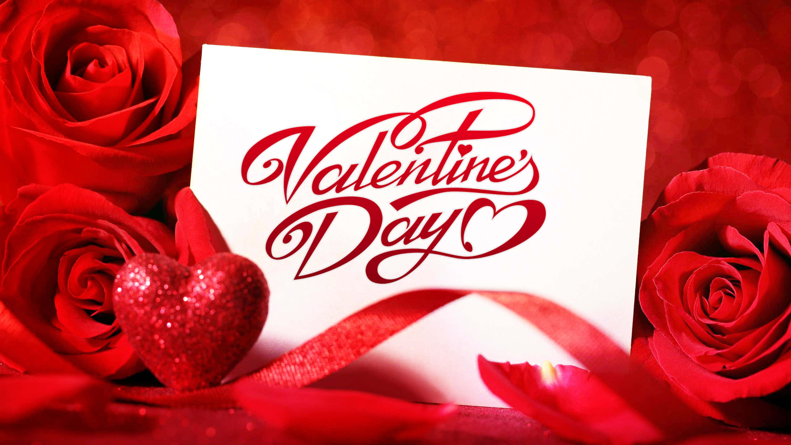 happy valentine's day 桌布 壁紙 — 一張白色情人節卡片，上面有草書字體，藏在鮮豔的紅玫瑰和閃閃發光的心形裝飾之間。