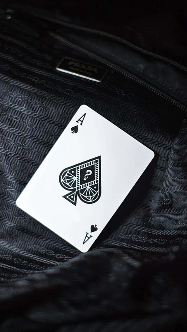 Card Games 桌布 壁紙 — 一張白色黑桃A牌放在有紋理的黑色Prada手袋上，帶有微妙的拉鍊和標誌。