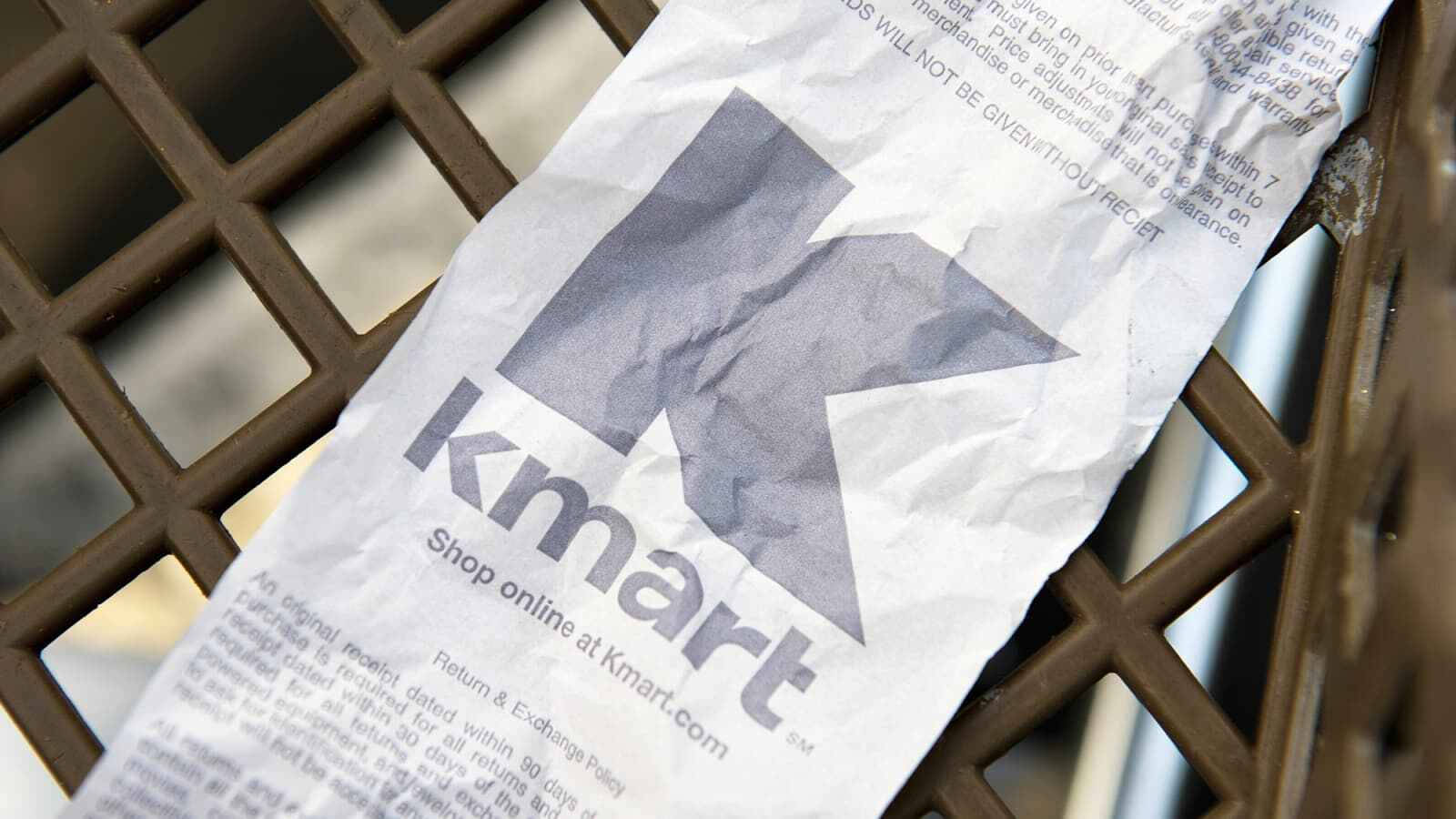supermarket 桌布 壁紙 — 一張皺巴巴的Kmart收據斜放在棕色塑膠購物車格柵上。