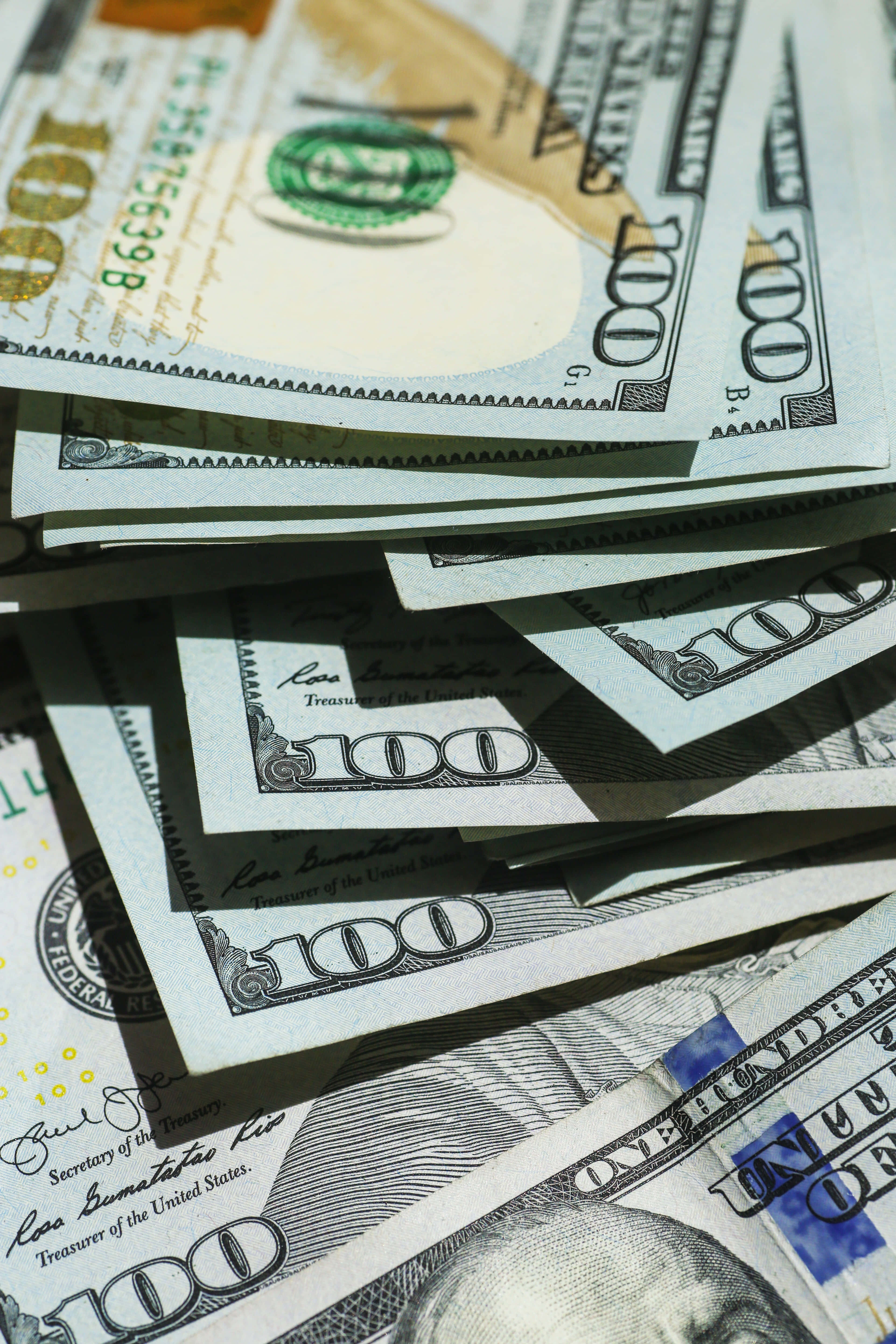 100 Dollar Bill 桌布 壁紙 — 一張皺巴巴的一百美元鈔票疊起並扇開的特寫，帶有銳利陰影和清晰細節。