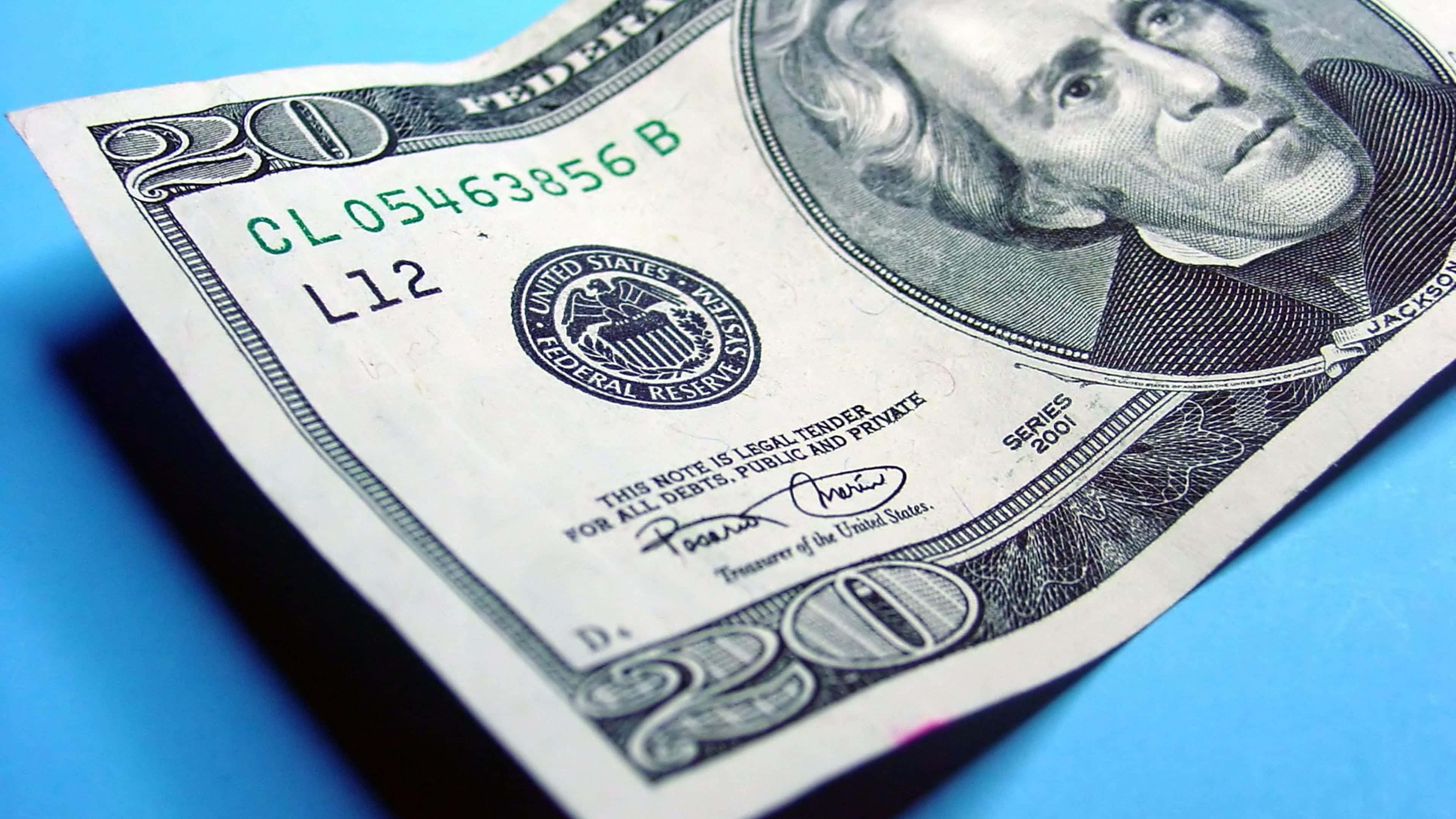 金錢 桌布 壁紙 — 一張皺巴巴的二十美元鈔票的特寫，放在鮮豔的藍色表面上，喬治·華盛頓的肖像清晰對焦。