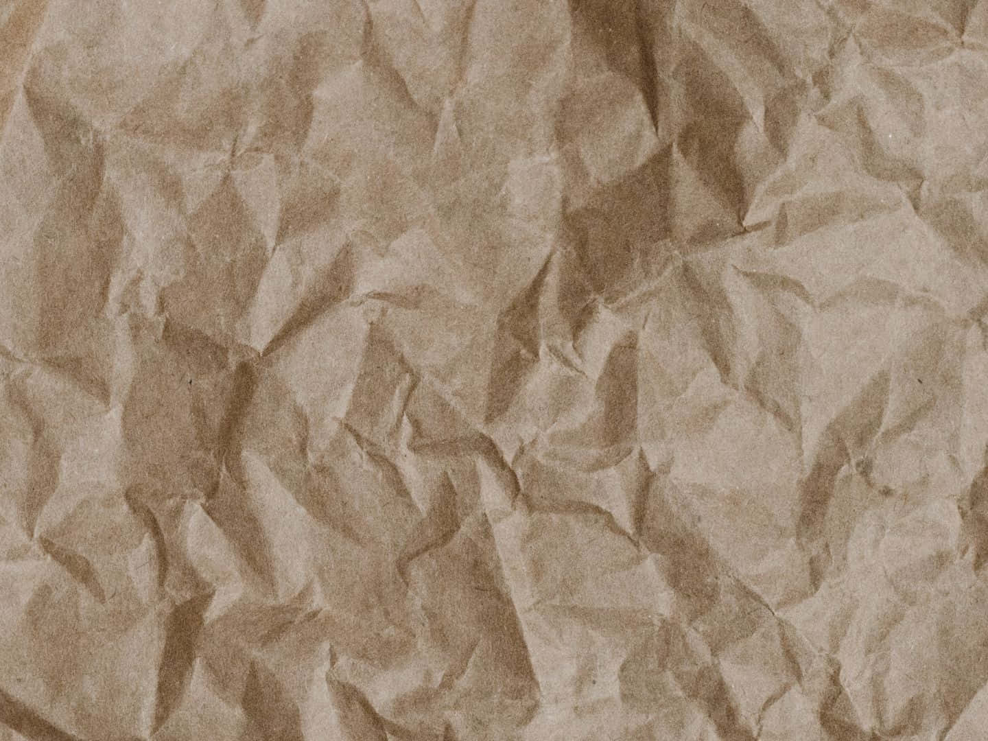 Old Paper 桌布 壁紙 — 一張皺巴巴的棕色紙張特寫，帶有深深的摺痕和柔和陰影，營造出觸感有機質感。