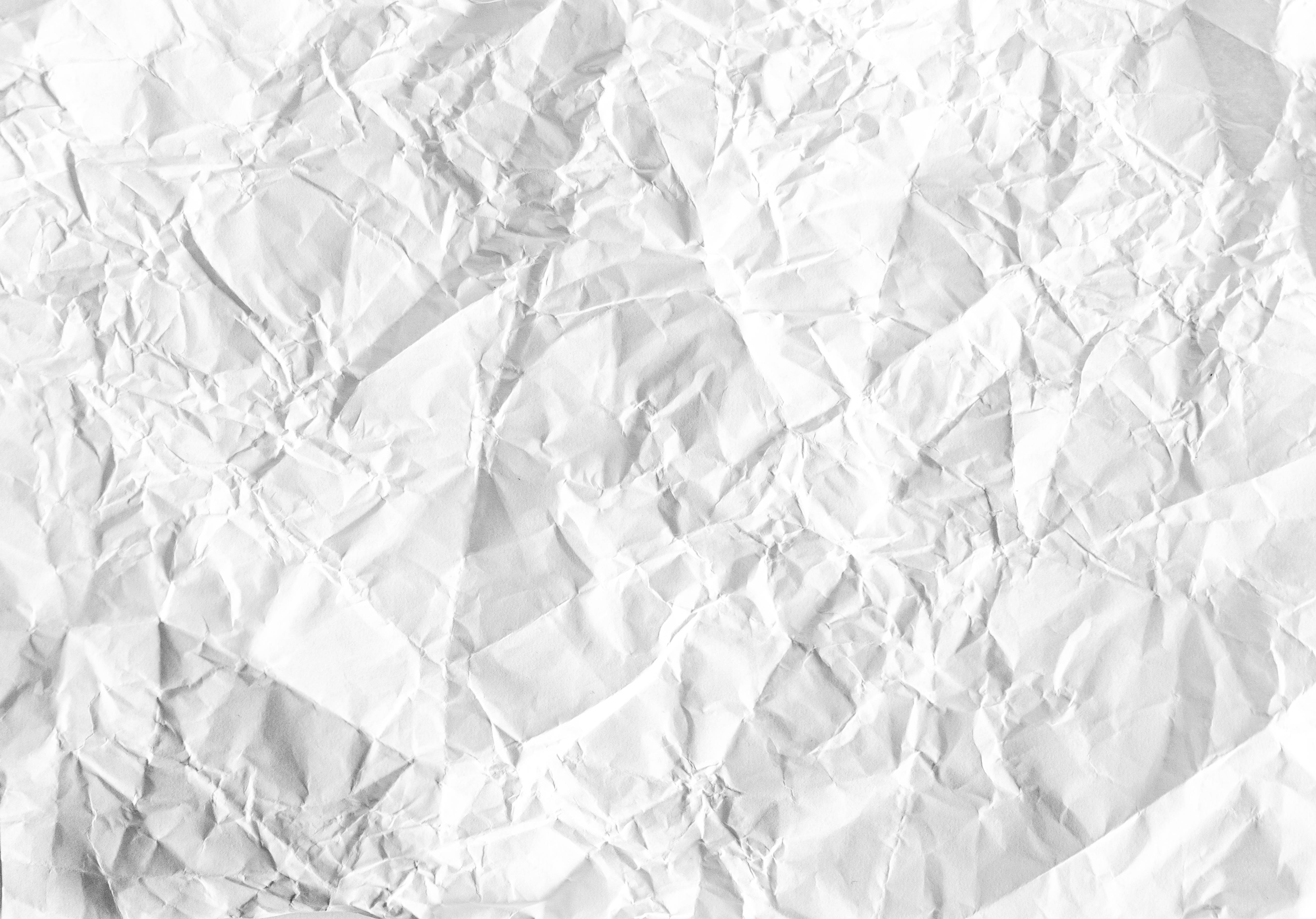 Paper Texture 桌布 壁紙 — 一張皺巴巴的白紙特寫，帶有深深的摺痕和柔和陰影，營造出有紋理的抽象表面。