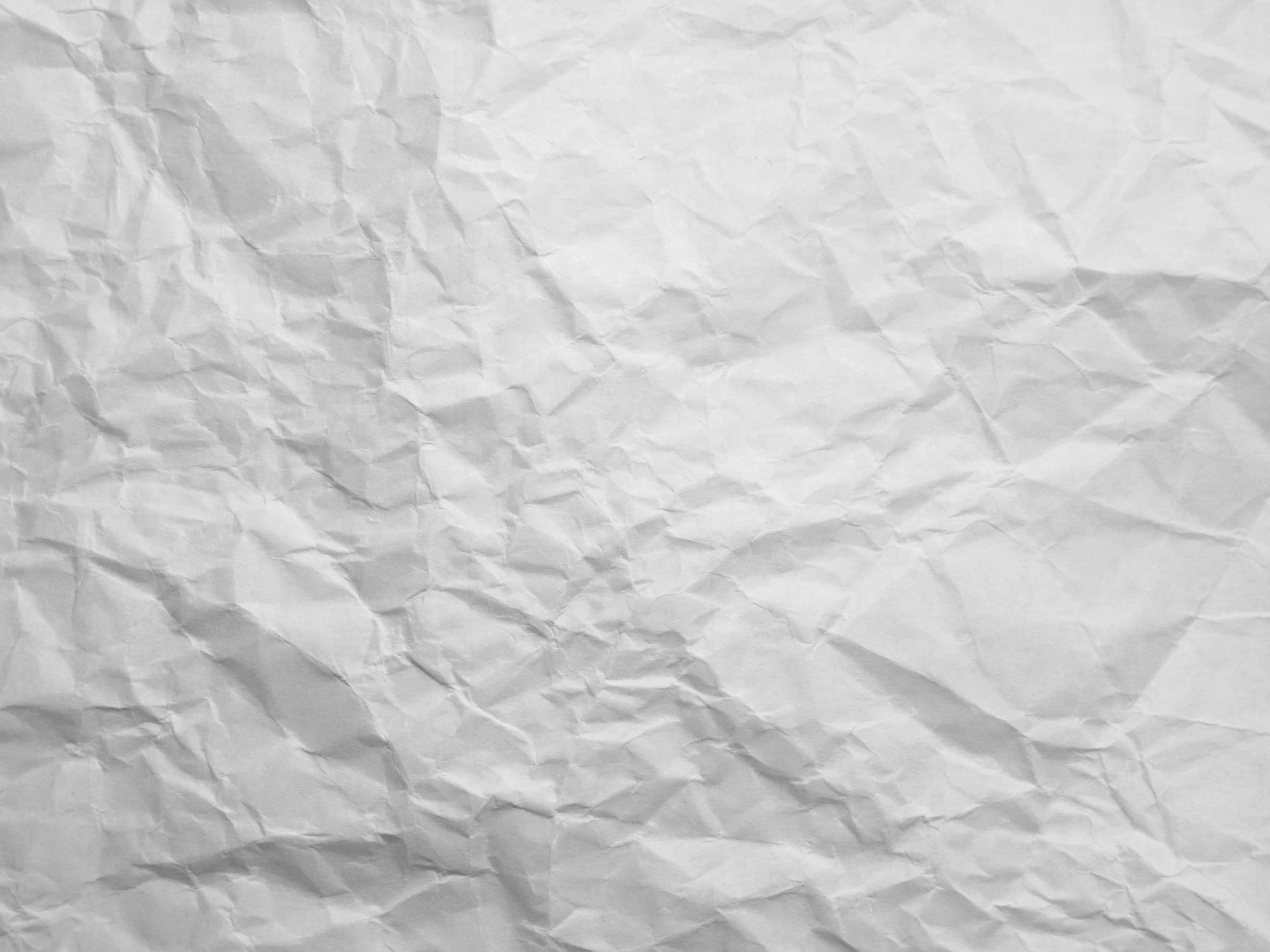 Paper Texture 桌布 壁紙 — 一張皺巴巴的白紙特寫，柔和陰影突出其紋理摺痕和皺褶。