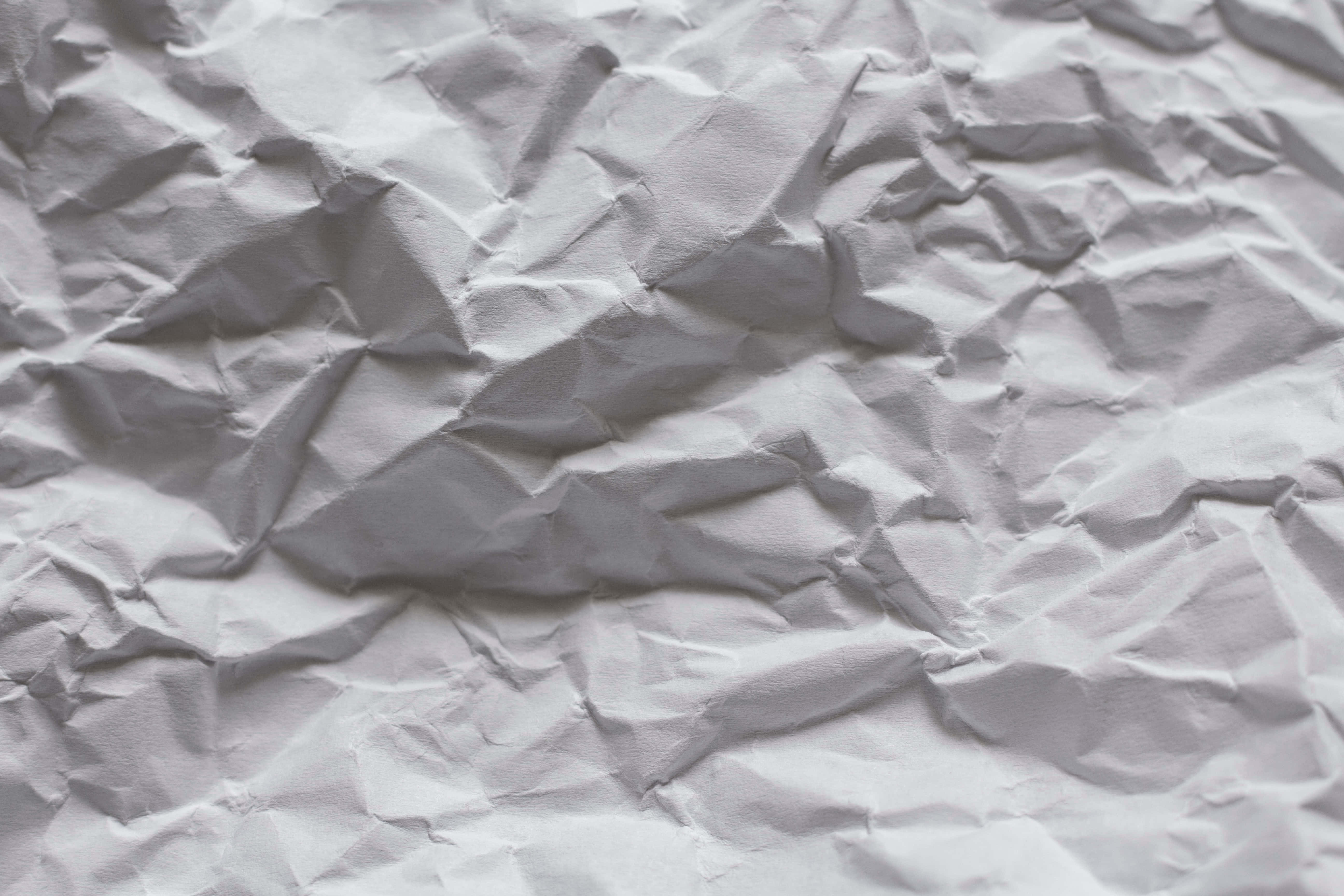 paper 桌布 壁紙 — 一張皺巴巴的白紙特寫，柔和陰影突顯其紋理摺痕和皺褶。