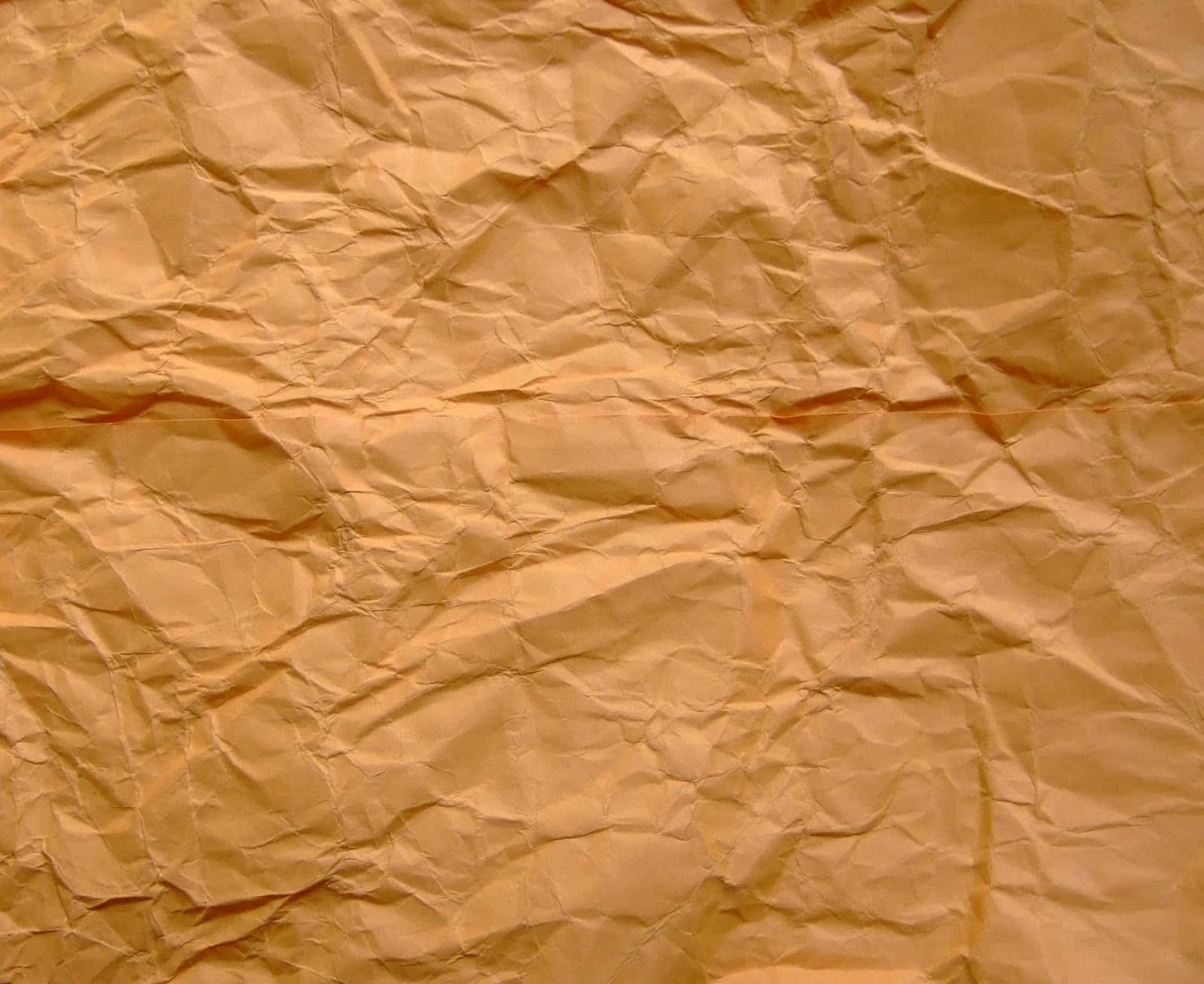 paper 桌布 壁紙 — 一張皺巴巴的金棕色紙張特寫，帶有深摺痕和柔和陰影，營造出觸感質感。