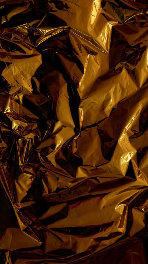 Shiny Gold 桌布 壁紙 — 一張皺巴巴的金箔特寫，深色陰影和明亮高光營造出奢華的紋理表面。