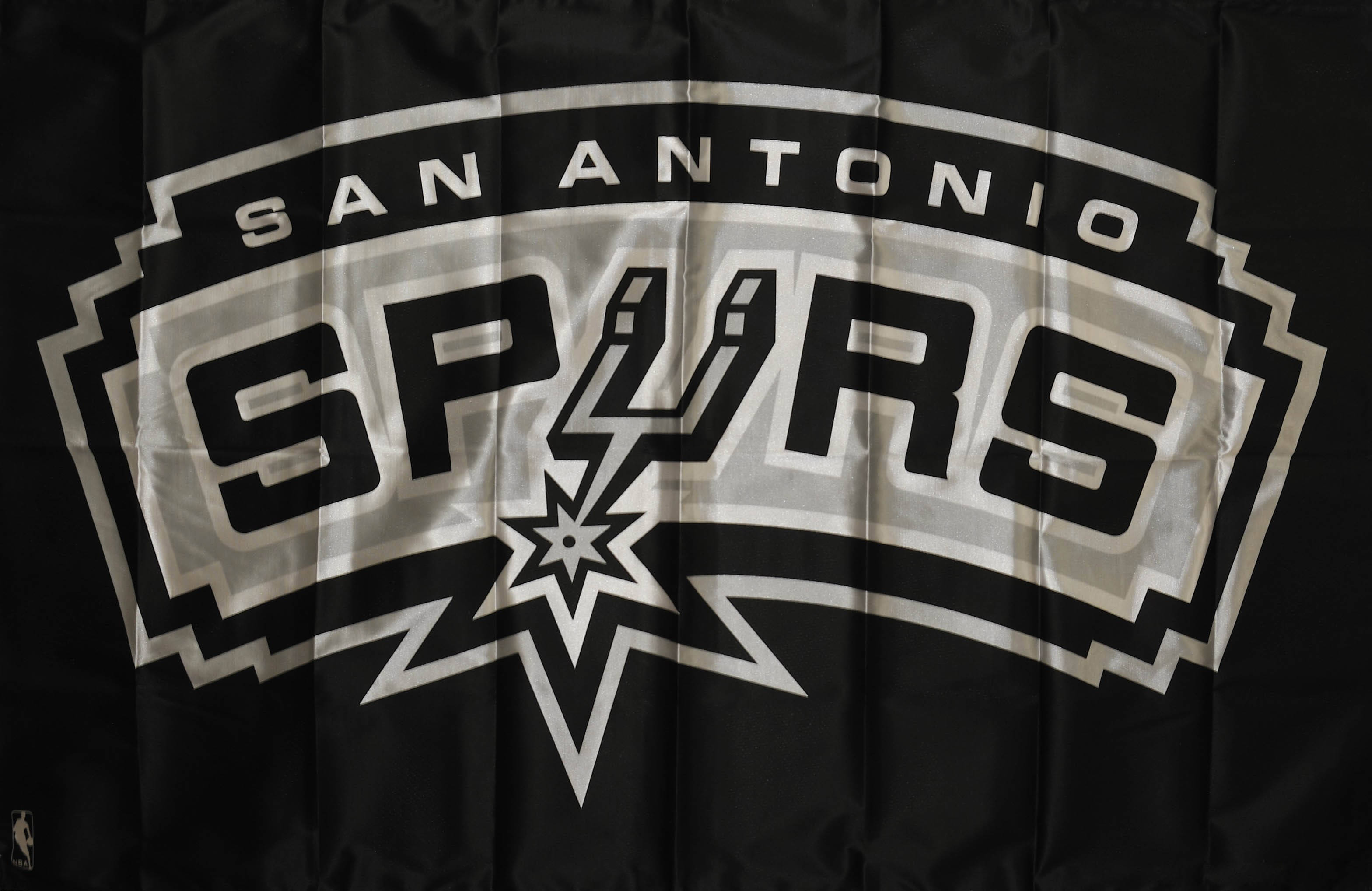 Spurs 桌布 壁紙 — 一張皺巴巴的黑色聖安東尼奧馬刺NBA旗幟特寫，帶有銀白色標誌。