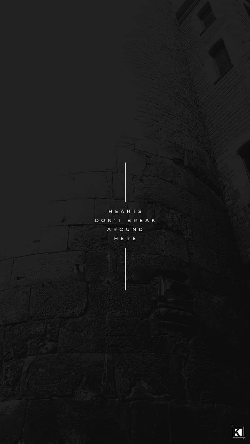 Broken Heart Aesthetics 桌布 壁紙 — 一張石塔牆壁的鮮明黑白照片，中央以極簡白色顯示文字 hearts don't break around here。