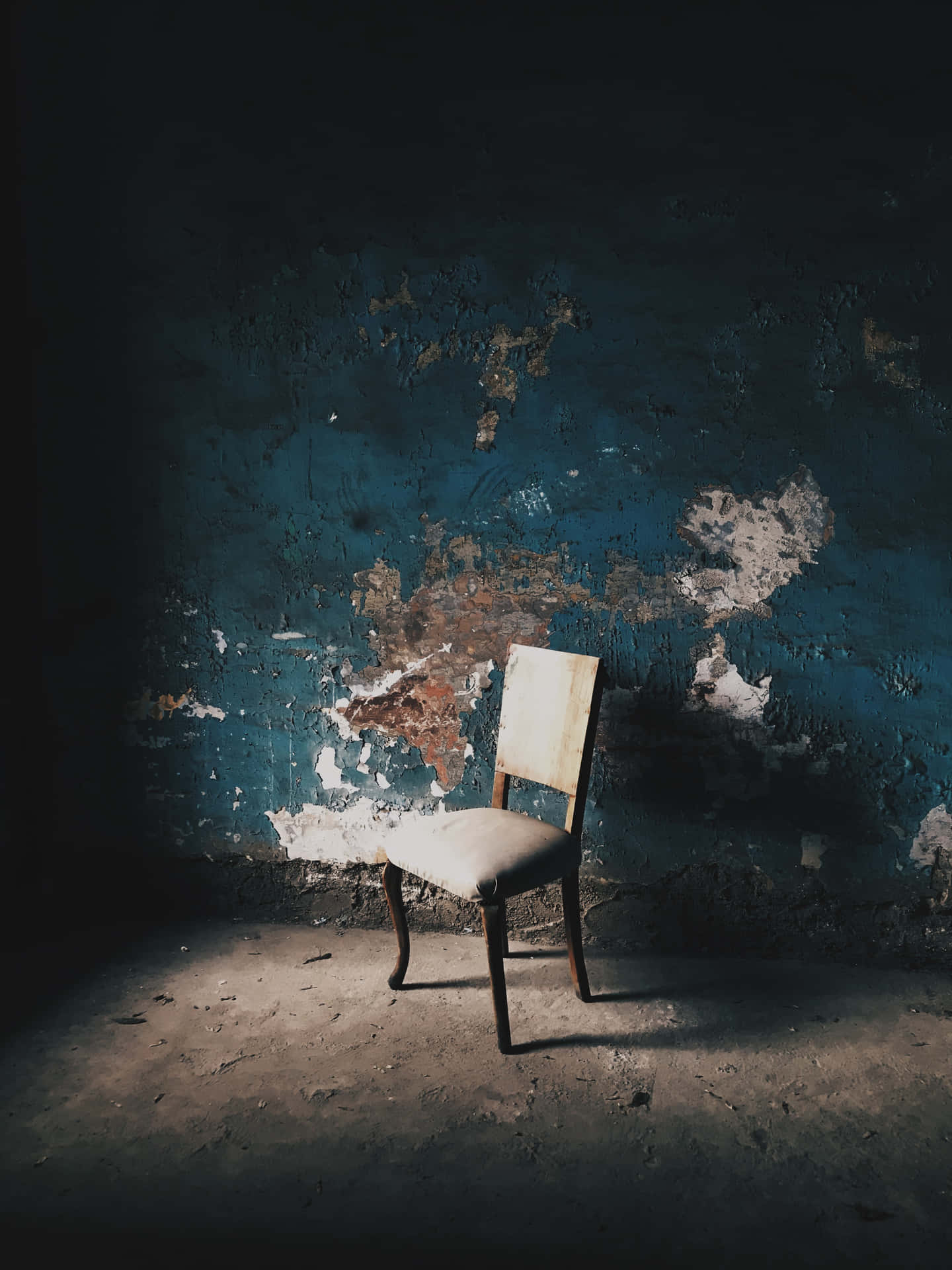 chair 桌布 壁紙 — 一張破舊的椅子獨自放在光線昏暗的房間裡，牆壁藍色剝落，地板佈滿灰塵。