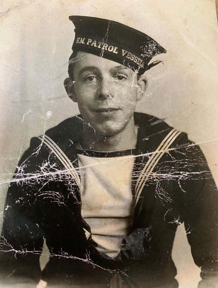 復古 桌布 壁紙 — 一張穿著 HM Patrol Vessels 制服的年輕水手的復古黑白肖像，照片上有明顯的裂紋和磨損。