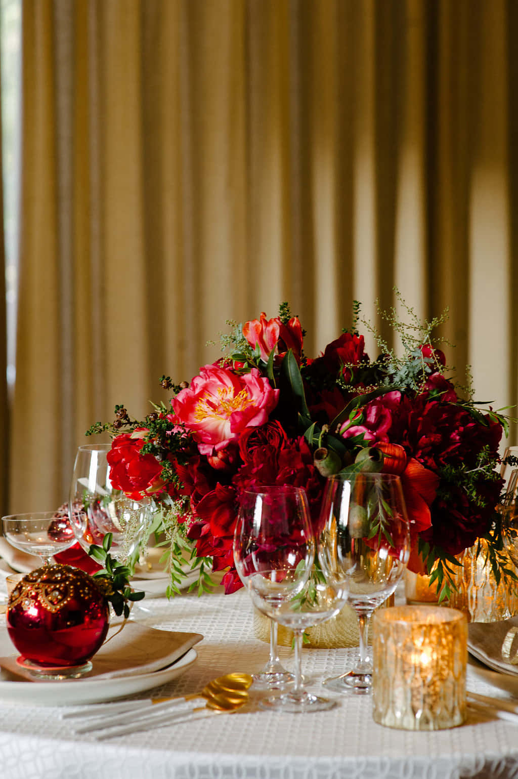 Centerpiece 桌布 壁紙 — 一張節日餐桌，擺放著深紅色花朵、金色裝飾和燭光，背景是溫暖的窗簾。