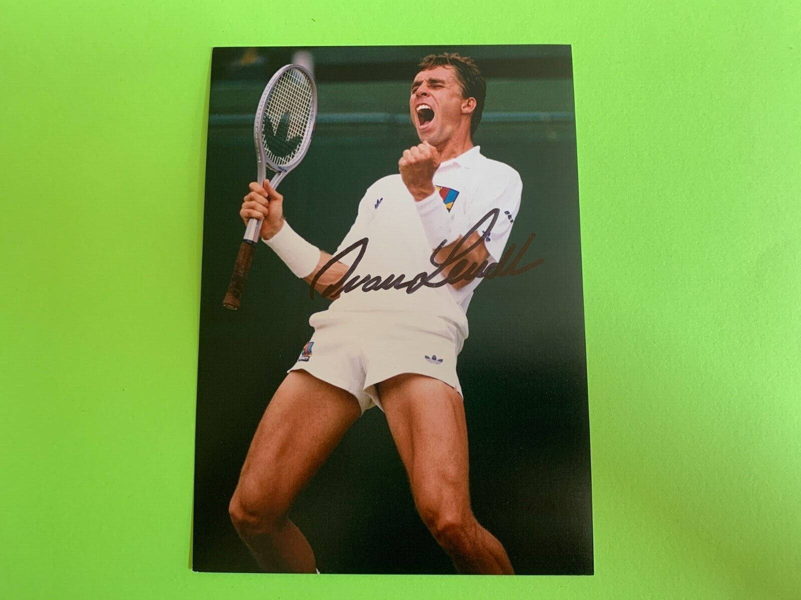 Tennis 桌布 壁紙 — 一張簽名照片，網球選手伊萬·倫德爾在亮綠色背景前高舉球拍、握緊拳頭慶祝勝利。