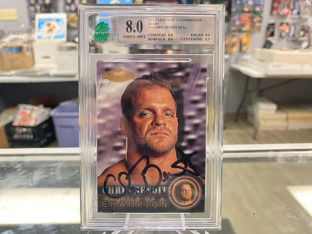 WWE 桌布 壁紙 — 一張簽名的Chris Benoit WWE交換卡放在保護盒中，置於收藏品店的玻璃展示面上。