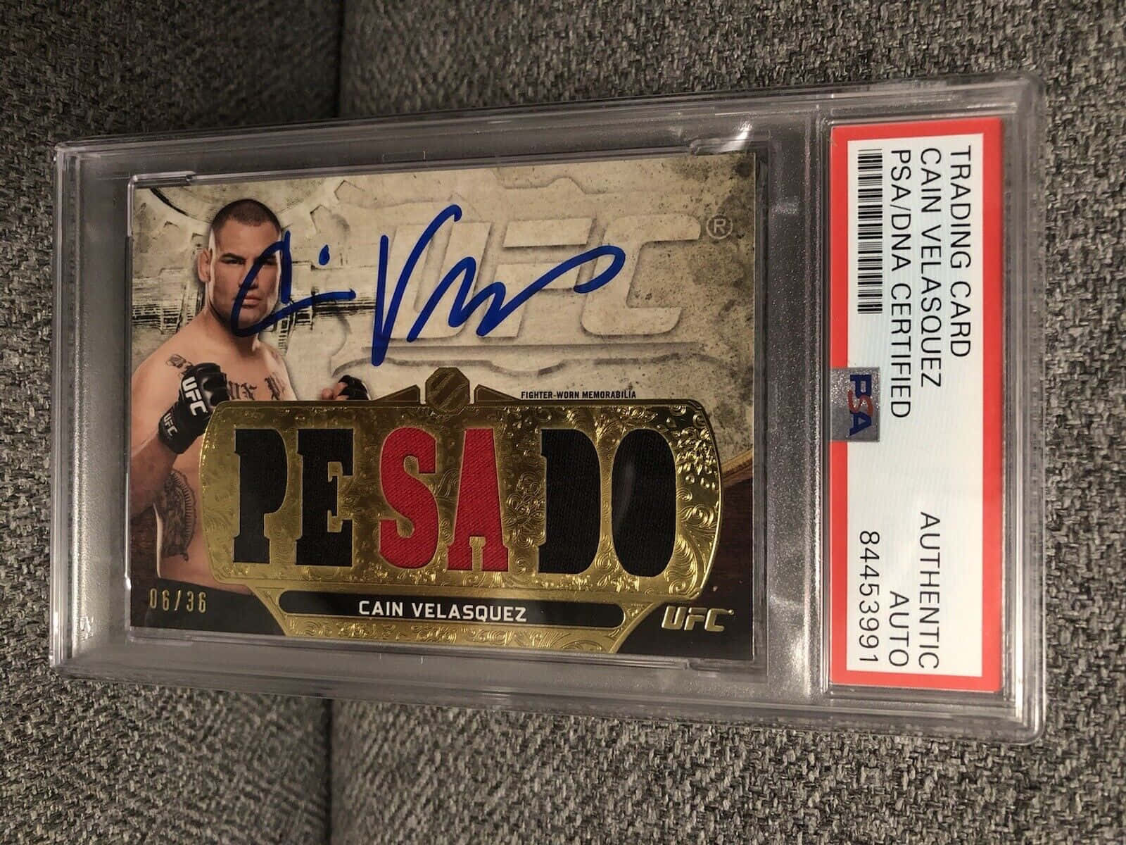UFC 桌布 壁紙 — 一張簽名的UFC交易卡，Cain Velasquez，在PSA認證的保護殼中，放置在灰色紋理表面上。