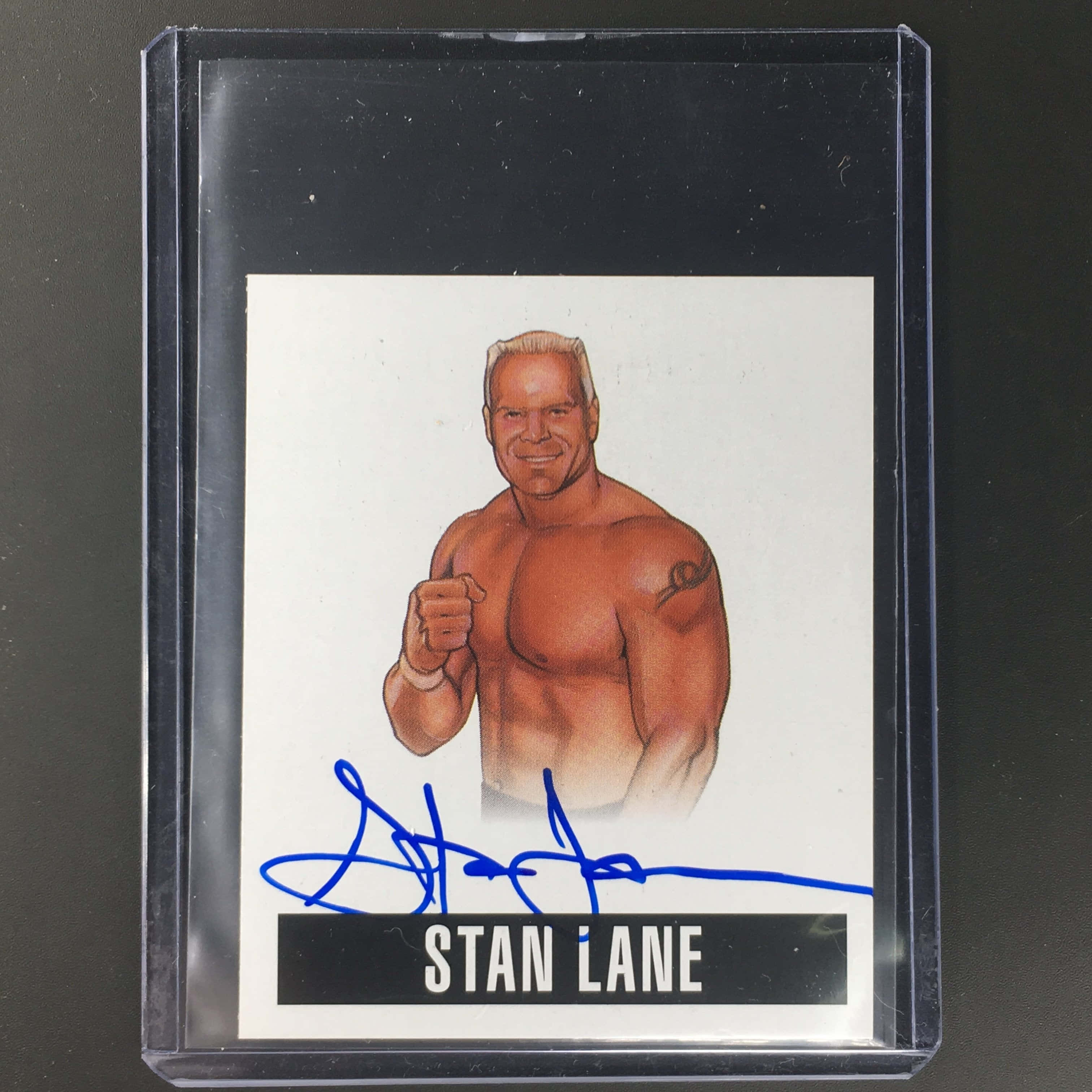摔角 桌布 壁紙 — 一張簽名的插圖摔角卡，Stan Lane 以自信姿勢出現，他的名字下方有藍色簽名。