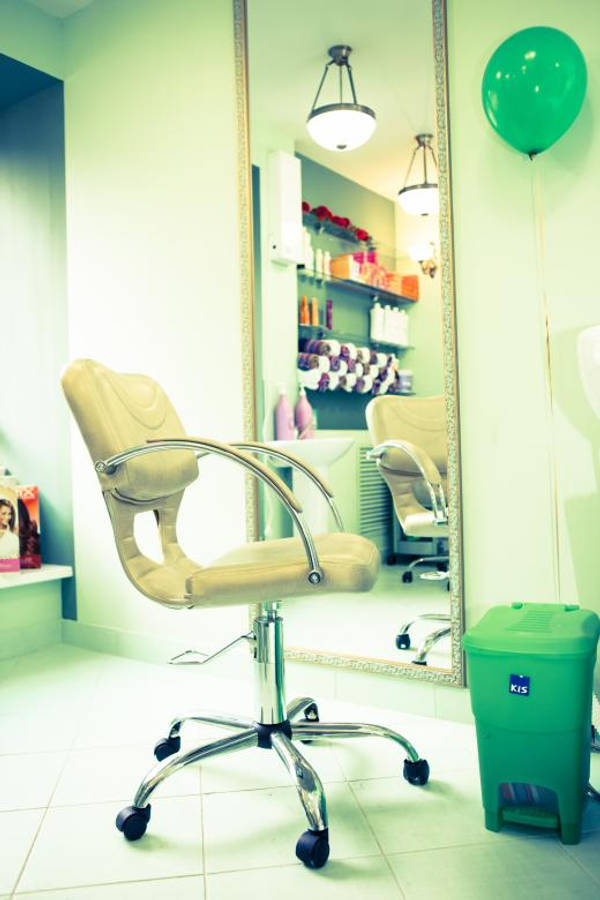 Salon 桌布 壁紙 — 一張米色沙龍椅搭配鍍鉻底座，放在明亮的綠色調髮廊中，配有鏡子和綠色垃圾桶。