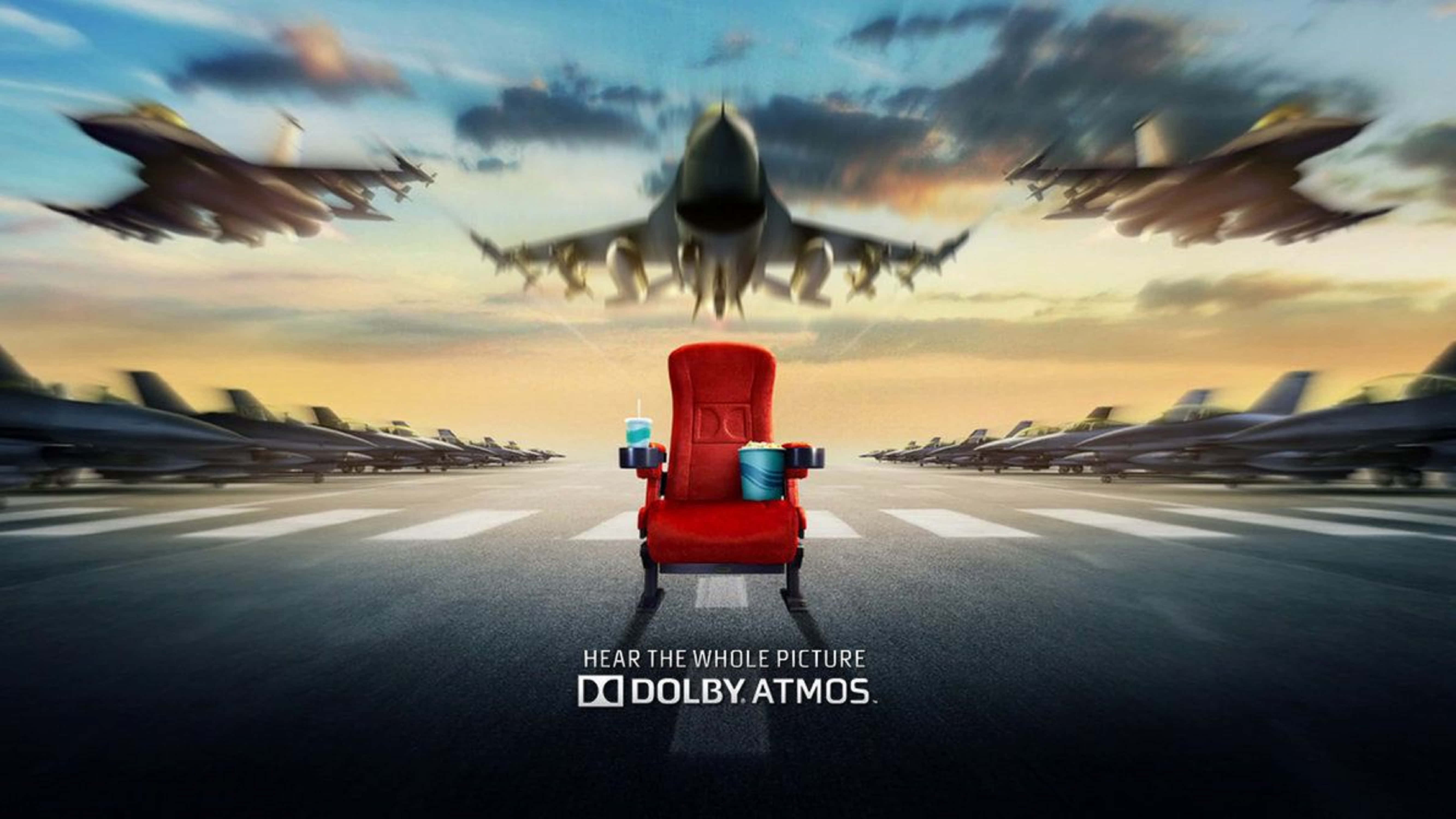4K Dolby Vision 桌布 壁紙 — 一張紅色電影院座椅放在機場停機坪中央，戰鬥機在金色夕陽天空下呼嘯而過。