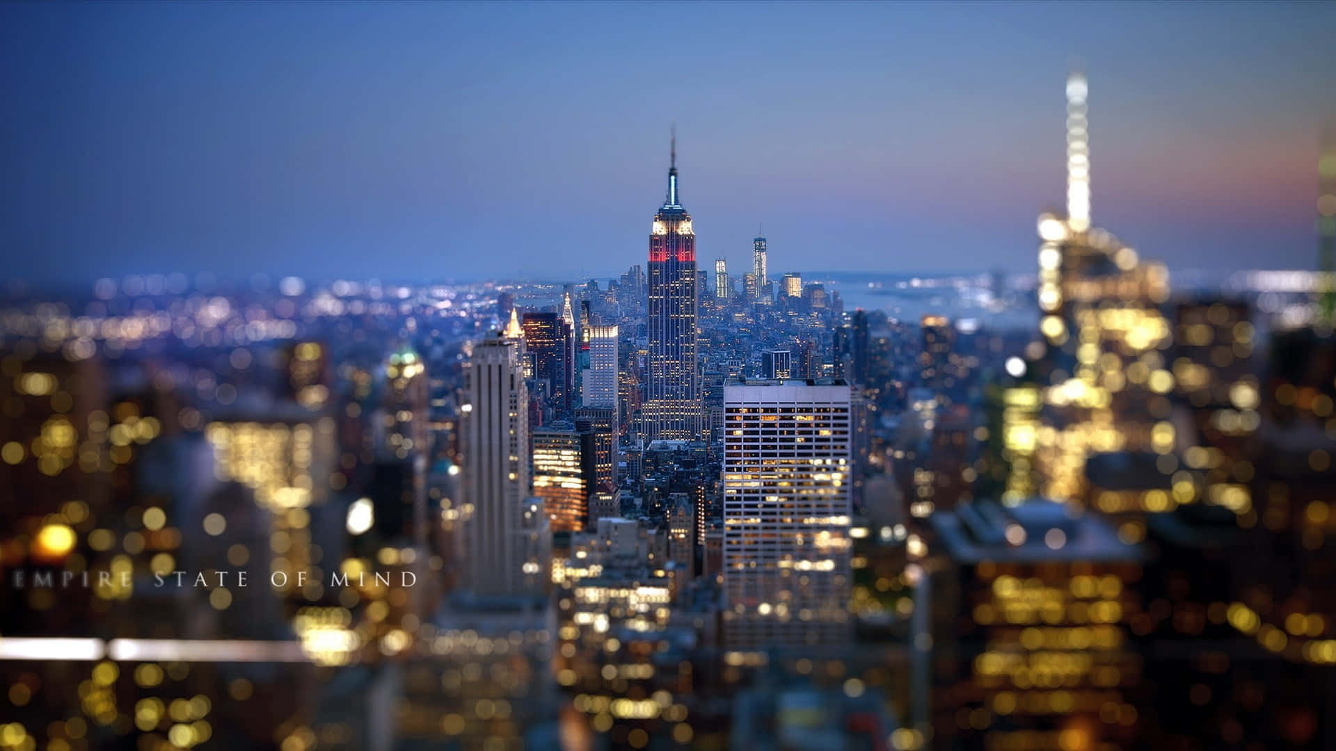New York 桌布 壁紙 — 一張紐約市黃昏時的移軸照片，帝國大廈亮起燈光，周圍的摩天大樓溫暖地發光。