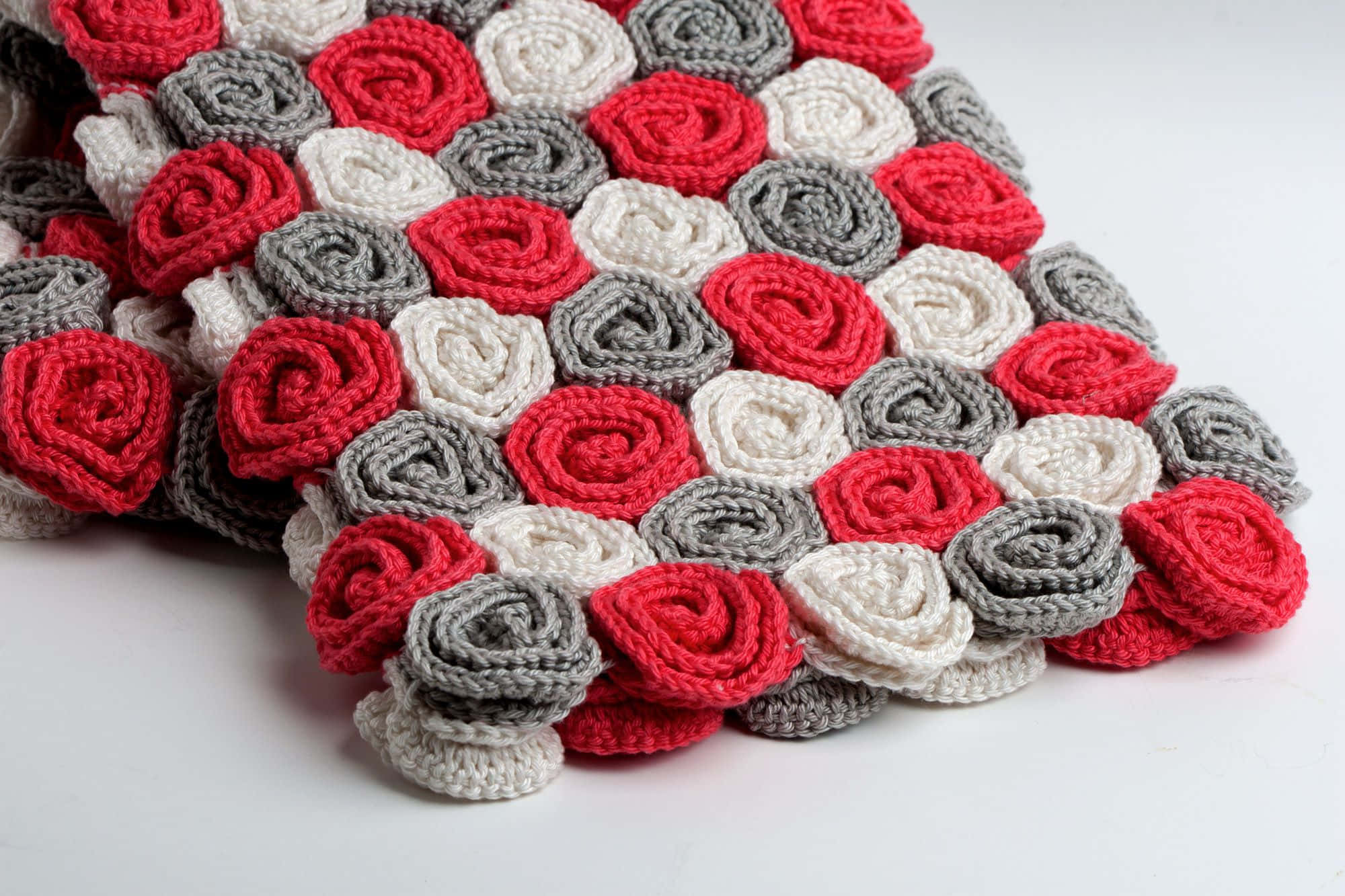 Crochet 桌布 壁紙 — 一張舒適的手工毯子，由紅色、灰色和奶油色的鉤針玫瑰圖案組成，排列成柔軟的紋理圖案。