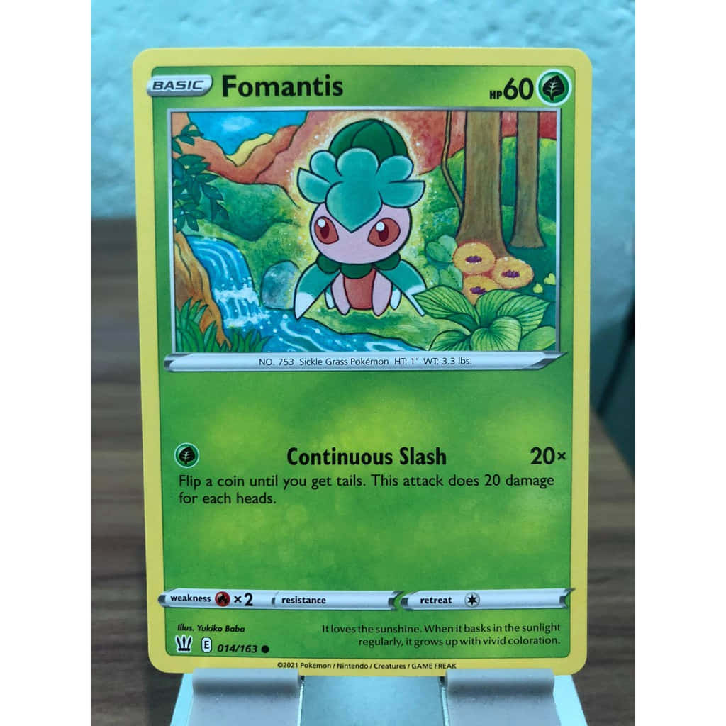 寶可夢 桌布 壁紙 — 一張色彩鮮豔的偽螳草寶可夢卡直立展示在支架上，背景是帶紋理的藍色牆壁。