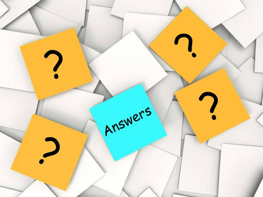 Questions 桌布 壁紙 — 一張藍色便利貼，上面寫著 'Answers'，周圍散落著帶有問號的黃色便利貼，背景為白色紙張。