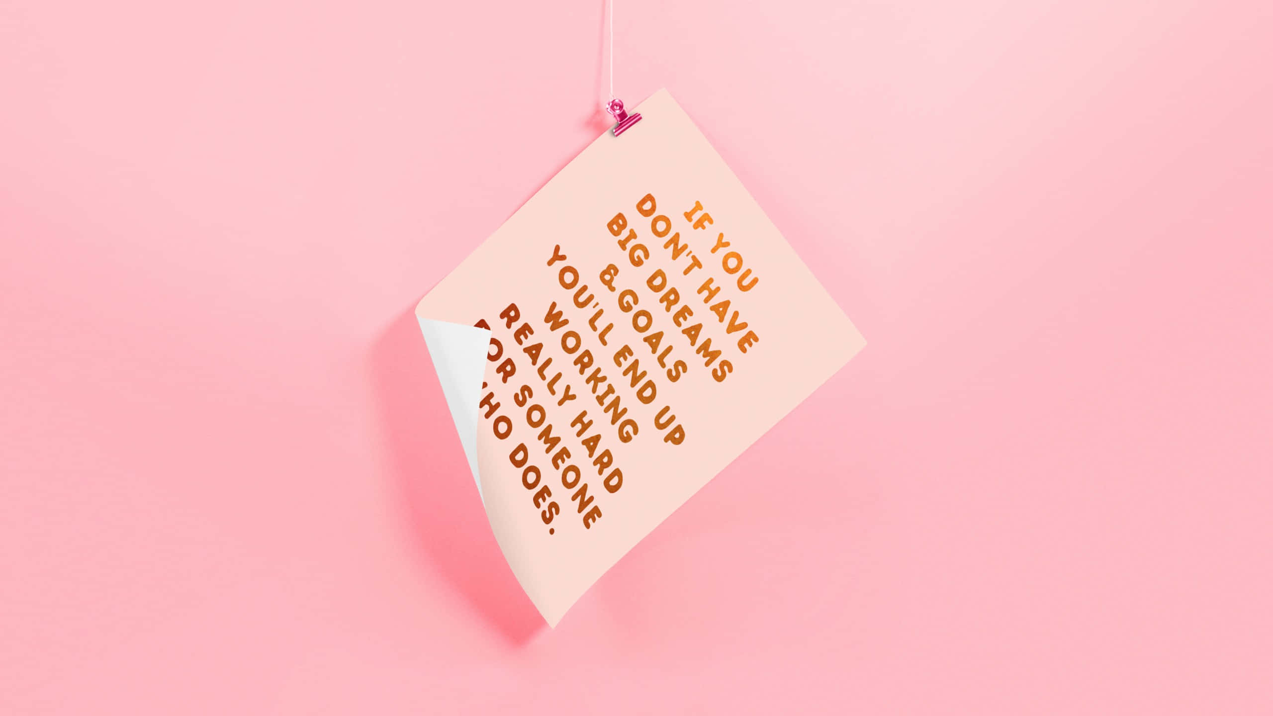 Minimalist Quote 桌布 壁紙 — 一張蜜桃色便利貼上寫有勵志文字，用粉紅色夾子掛在柔和粉紅色背景上。