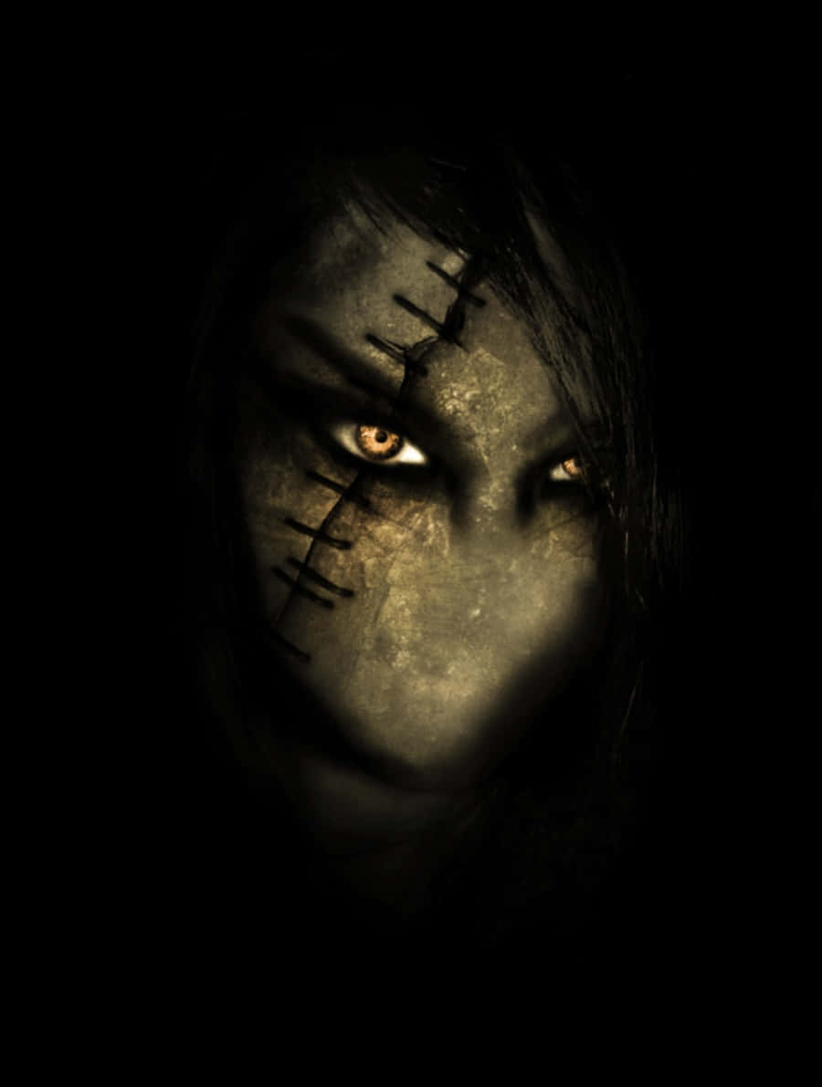 Scary Face 桌布 壁紙 — 一張被縫合得令人毛骨悚然的臉，帶著發光的琥珀色眼睛，從黑暗中以令人心寒的特寫出現。