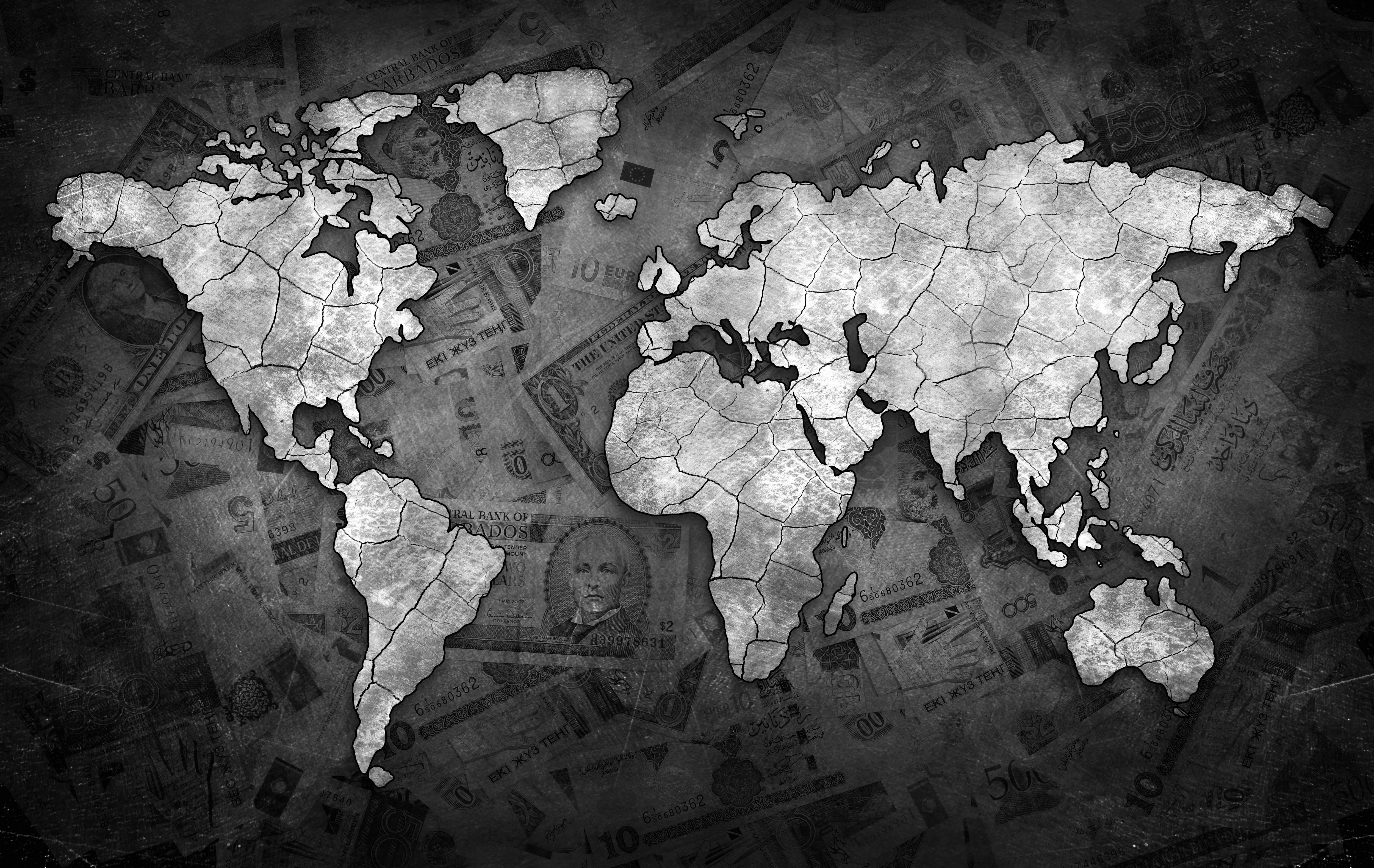 World Map Desktop 桌布 壁紙 — 一張褪色的全球貨幣紙幣拼貼中，浮現出一個裂開的世界地圖剪影。