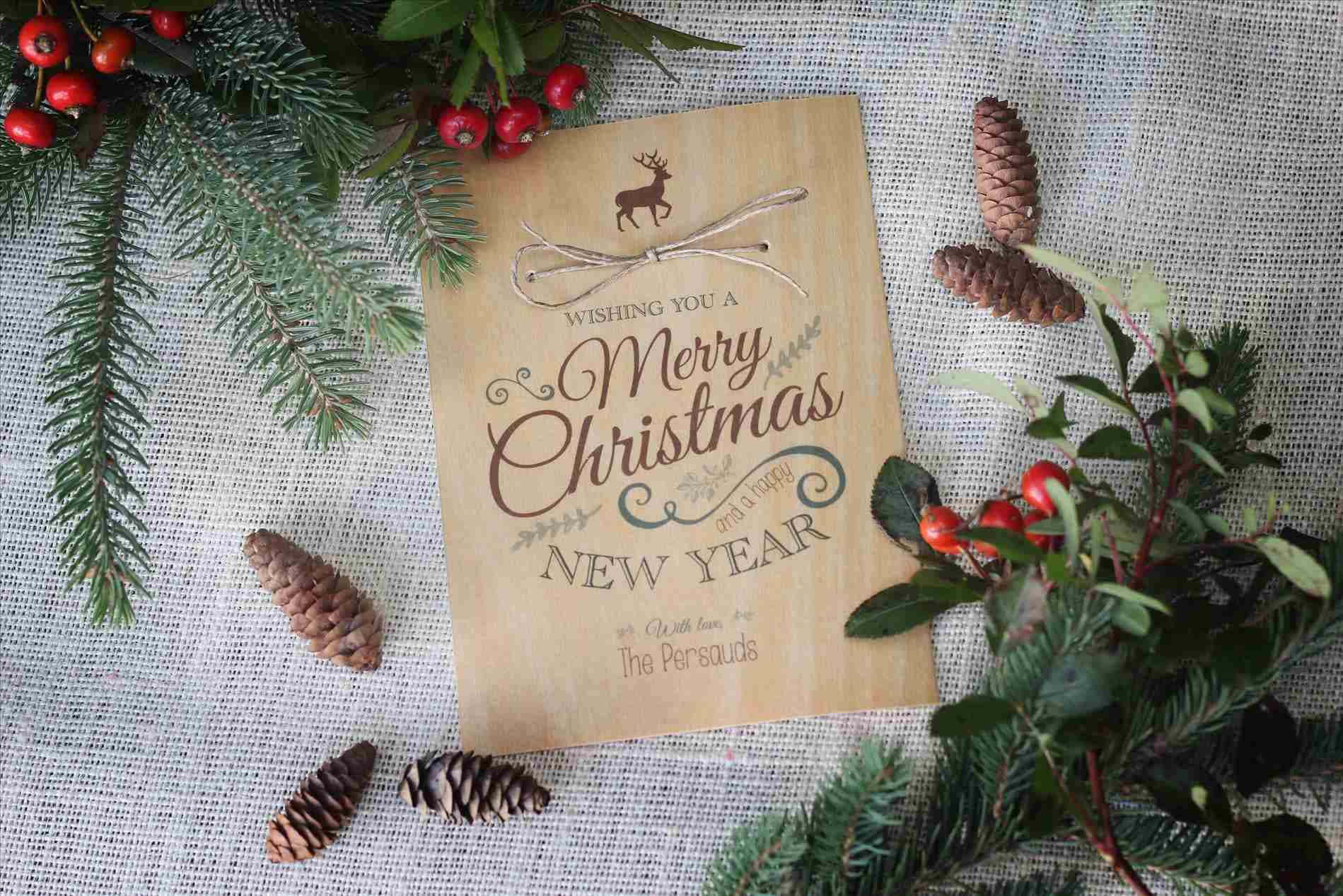 鄉村聖誕 桌布 壁紙 — 一張質樸的木製賀卡，上面寫著「Wishing You a Merry Christmas and Happy New Year」，周圍環繞著松枝、松果和紅色漿果，背景是帶有紋理的亞麻布。