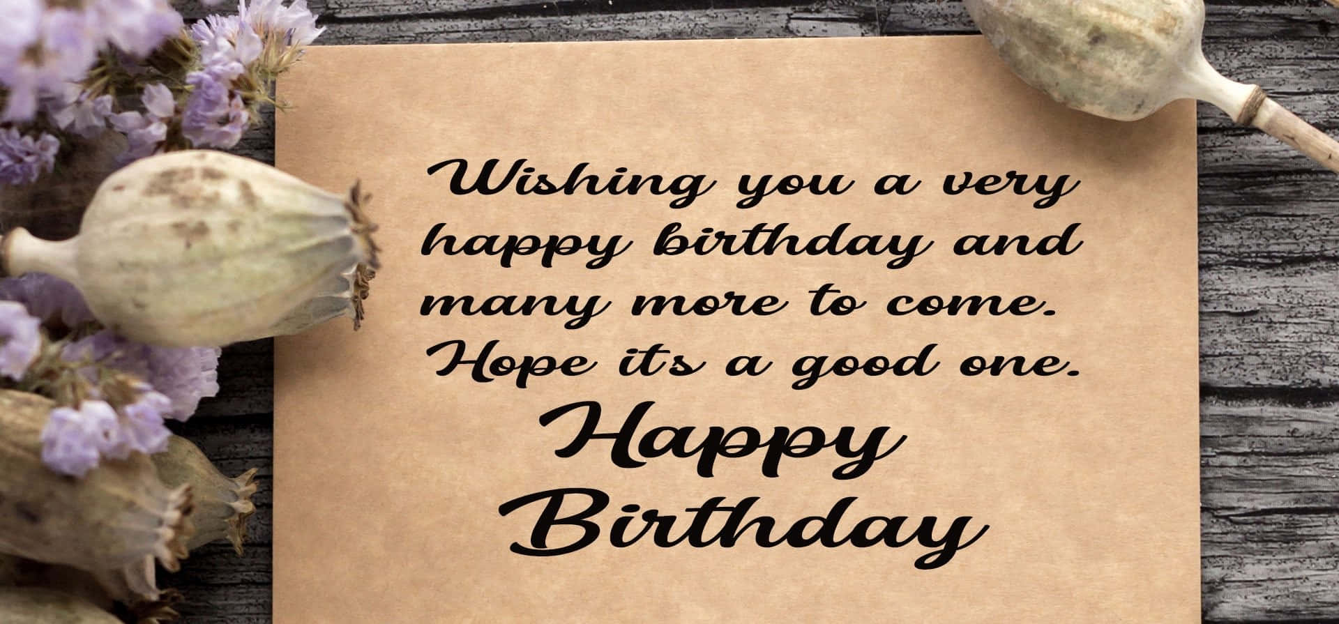 Birthday Wishes 桌布 壁紙 — 一張質樸的生日卡，帶有優雅的手寫字體，放置在風化的木頭上，兩側是乾燥的罌粟莢和薰衣草花。