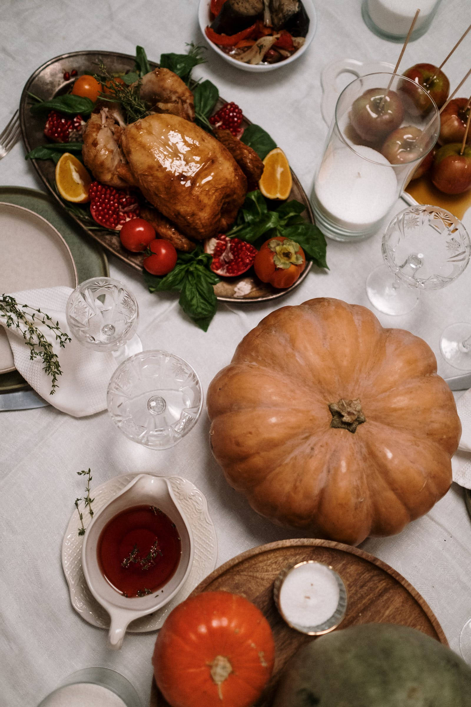 Thanksgiving Day 桌布 壁紙 — 一張質樸的秋季餐桌，擺放著烤火雞、石榴、柳橙和南瓜，在溫暖柔和的光線下。