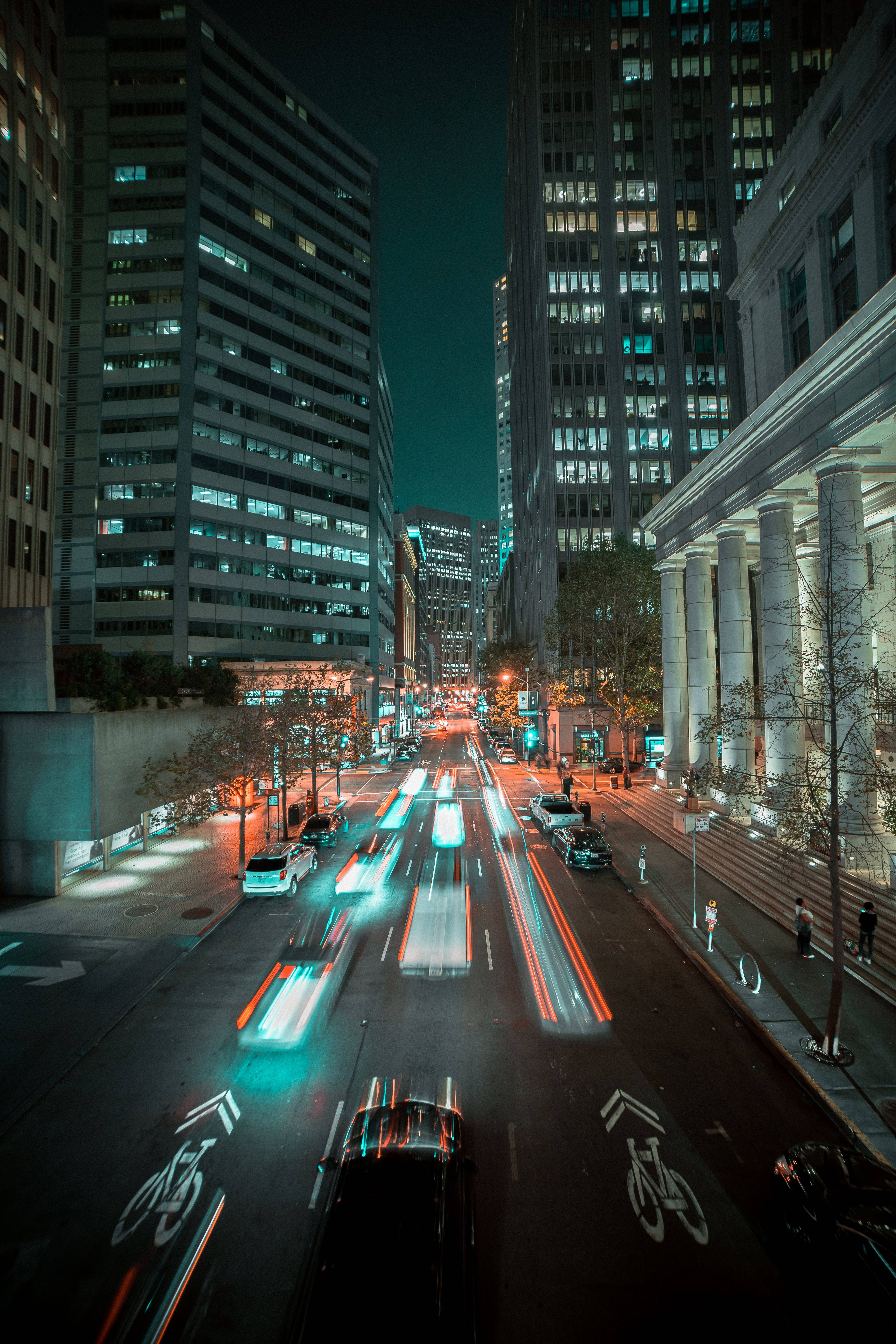 4K iPhone 6 plus 桌布 壁紙 — 一張長時間曝光拍攝的繁華城市街道夜景，高聳摩天大樓之間有汽車燈光形成的流線。