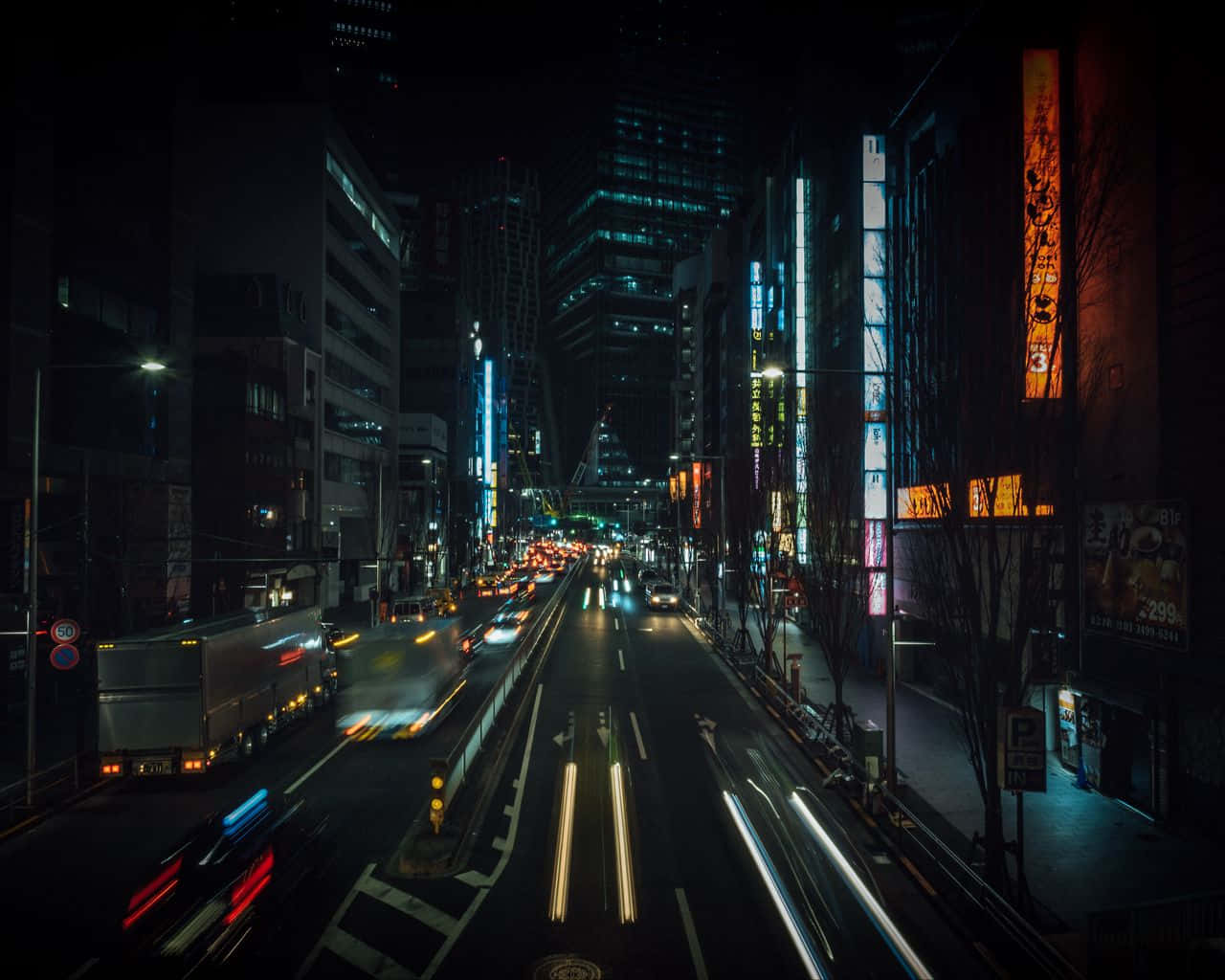 Night Street 桌布 壁紙 — 一張長時間曝光拍攝的繁華霓虹燈城市街道夜景，帶有流動的車燈軌跡和高聳的建築物。