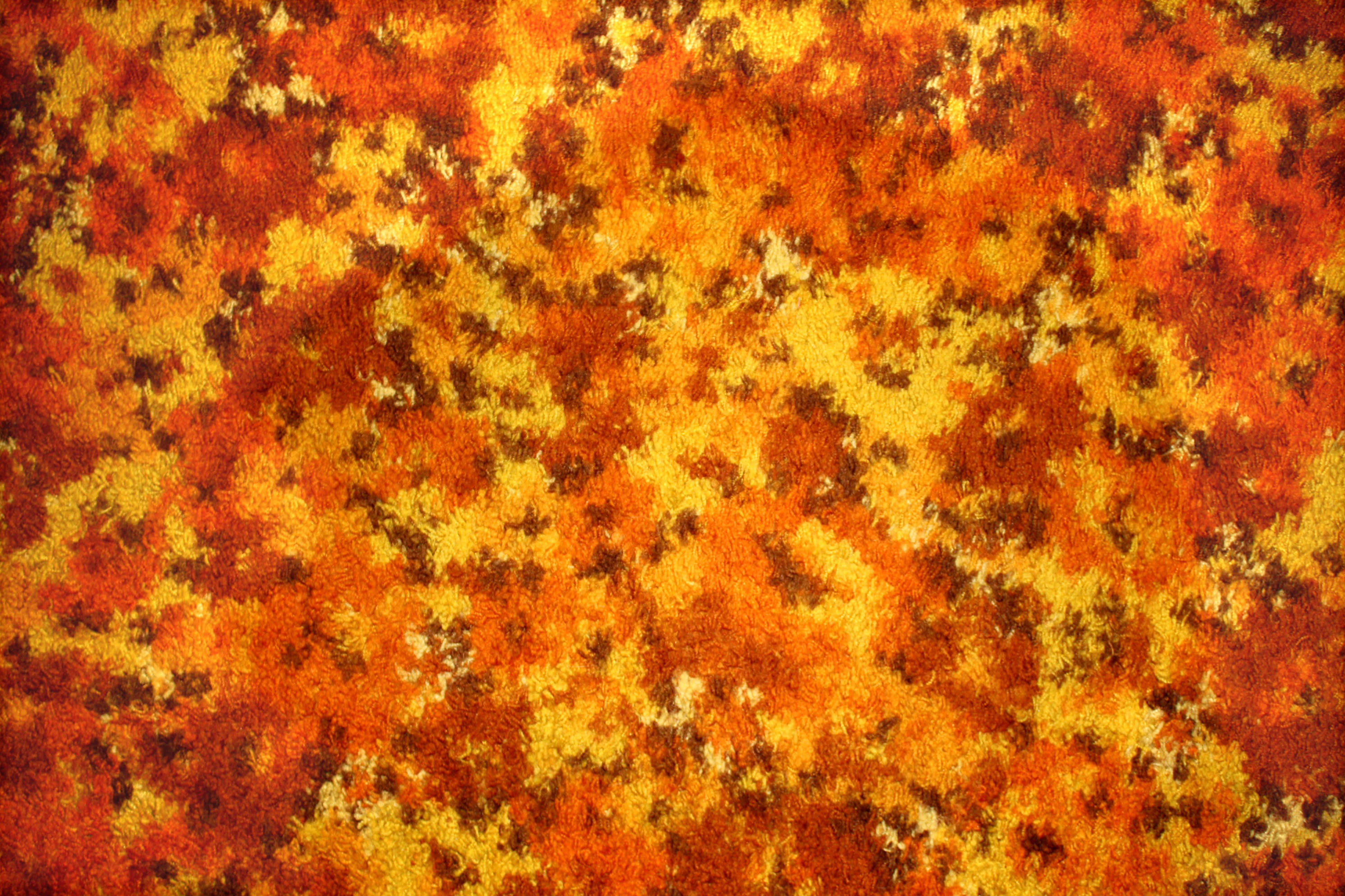Carpet Texture 桌布 壁紙 — 一張長毛地毯的特寫，帶有火熱的橙黃色和棕色抽象圖案。