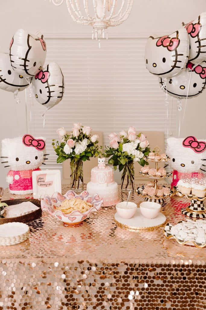 Hello Kitty Party 桌布 壁紙 — 一張閃閃發光的粉紅色亮片桌子，裝飾著Hello Kitty氣球、蛋糕和鮮花，置於吊燈下。