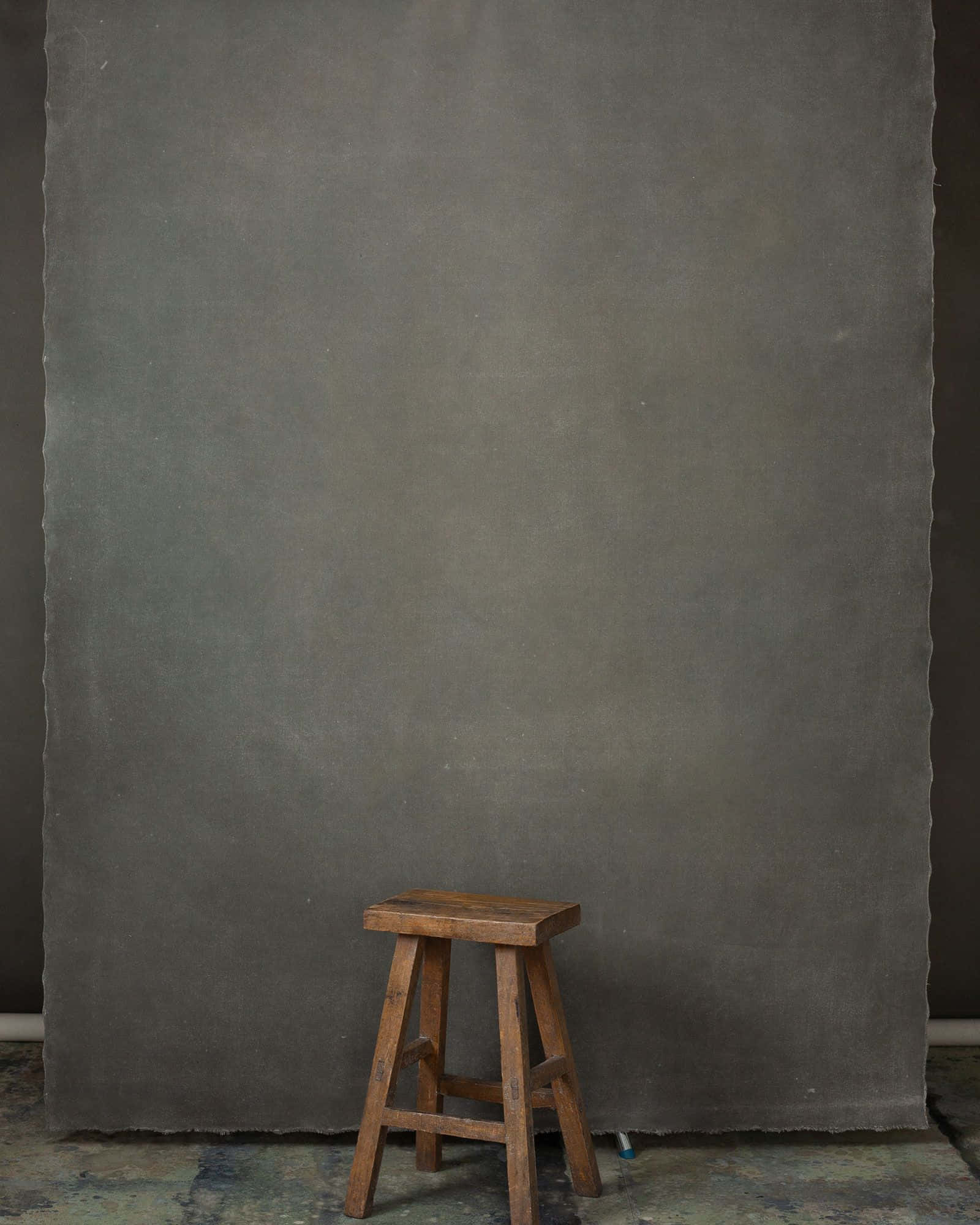 Minimalist Photography 桌布 壁紙 — 一張風化的木凳立在昏暗工作室空間中，前面是大型紋理灰色背景。