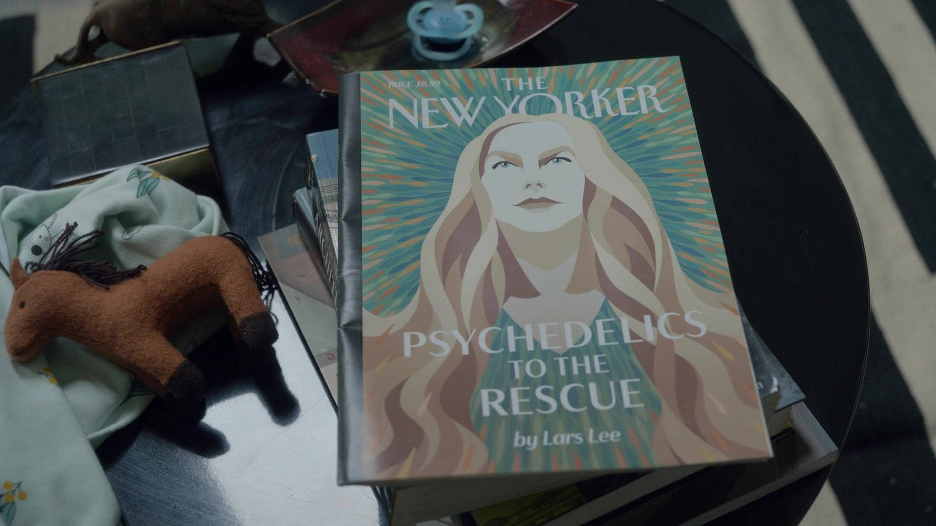 九個完美陌生人 桌布 壁紙 — 一張風格化的雜誌封面，標題為「Psychedelics to the Rescue」，放在深色桌子上的書本上，旁邊有一個氈製馬玩具和奶嘴。