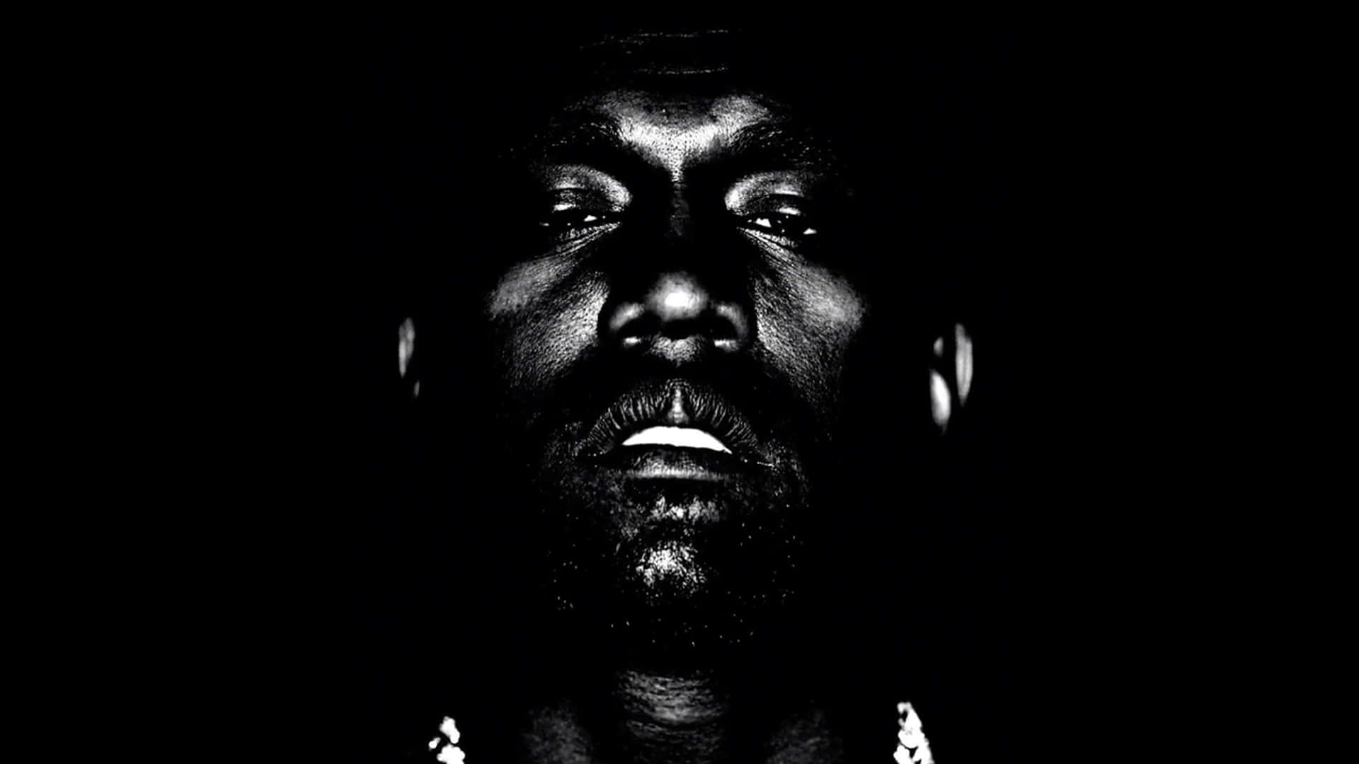 Kanye West Yeezus 桌布 壁紙 — 一張高對比度的黑白人像，男人的臉在黑暗背景下被戲劇性的側光照亮。