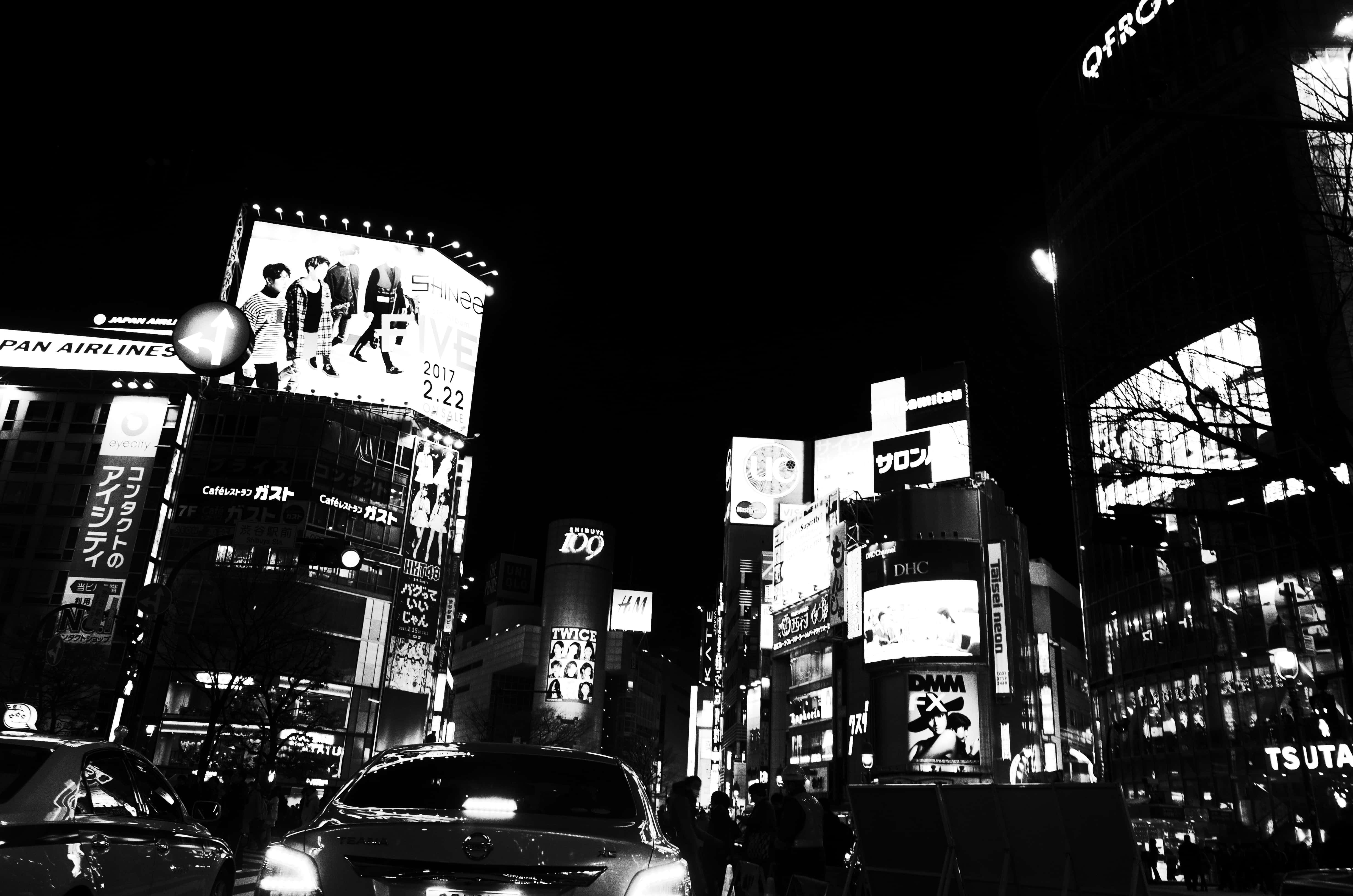 東京 桌布 壁紙 — 一張高對比度的黑白夜景照片，拍攝了東京一條繁忙的街道，充滿了發光的廣告牌和霓虹燈。