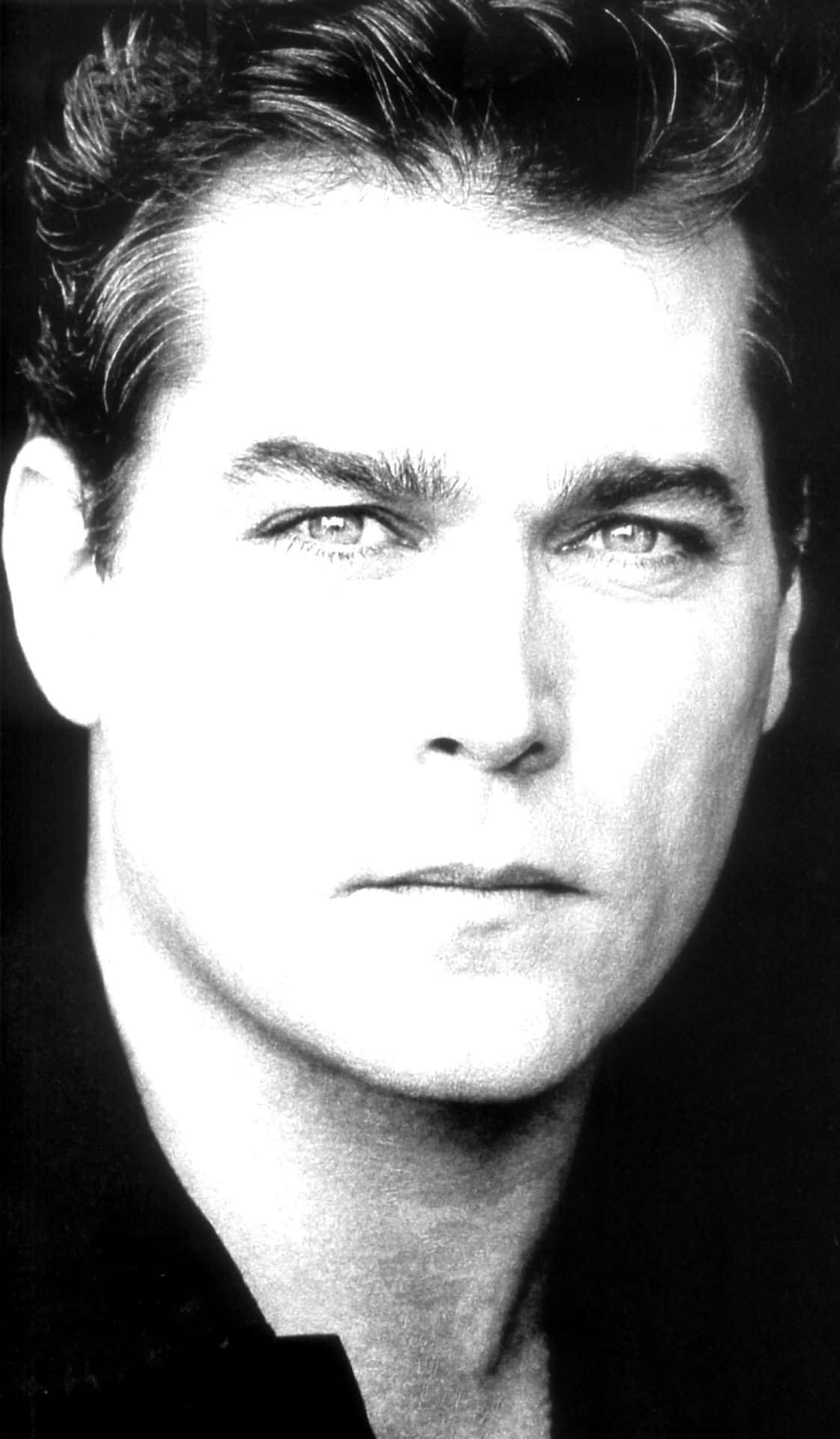 Ray Liotta 桌布 壁紙 — 一張高對比度的黑白肖像照，捕捉一位眼神銳利、頭髮造型時尚的男子直視鏡頭。