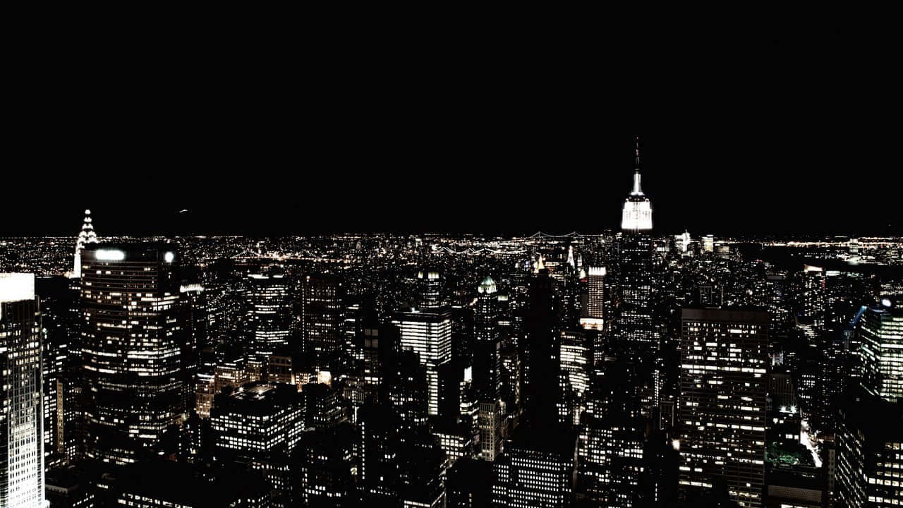 720p Empire State Building 桌布 壁紙 — 一張高對比度的黑白鳥瞰圖，展現夜晚的紐約市，帝國大廈閃耀著明亮的光芒。