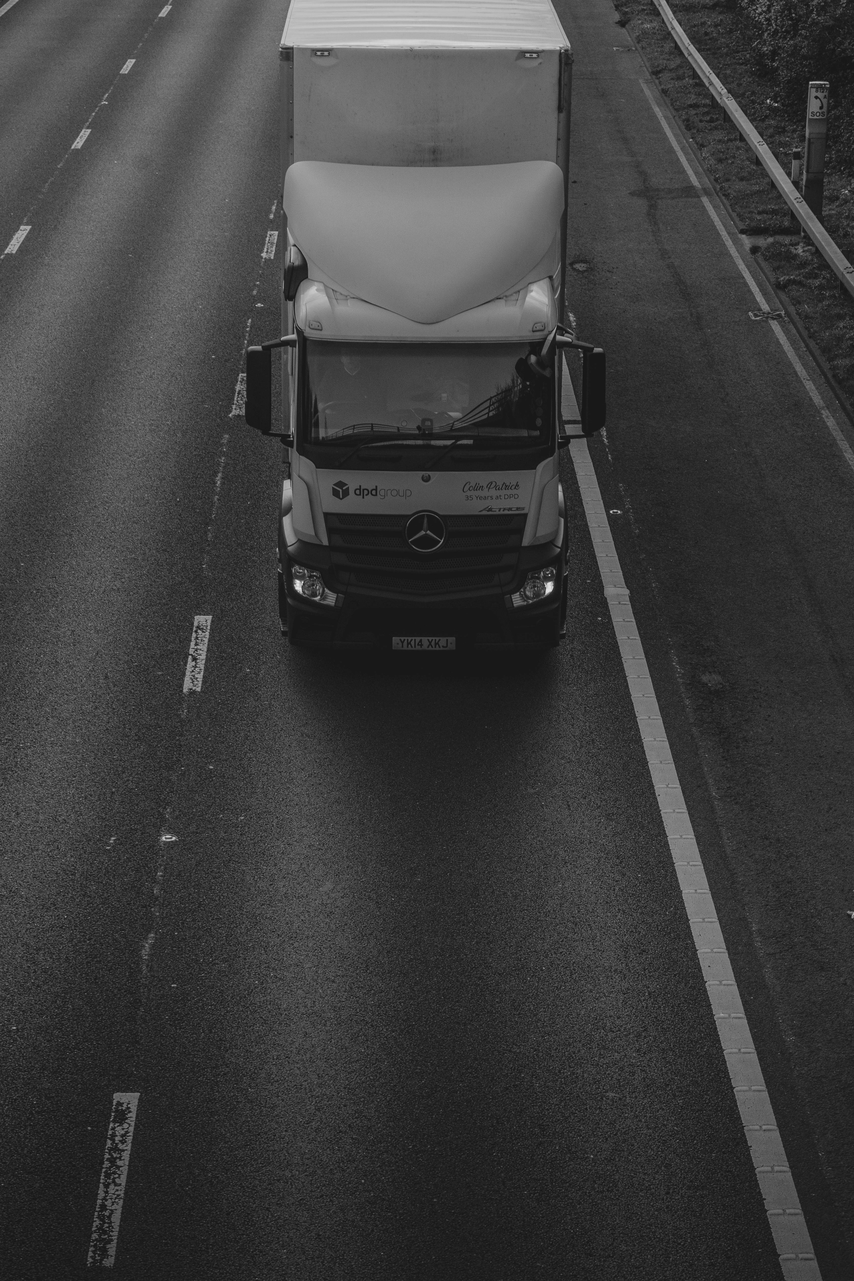Truck 桌布 壁紙 — 一張高角度黑白照片，拍攝一輛梅賽德斯-奔馳半掛卡車在潮濕的高速公路上行駛，車道標記清晰。