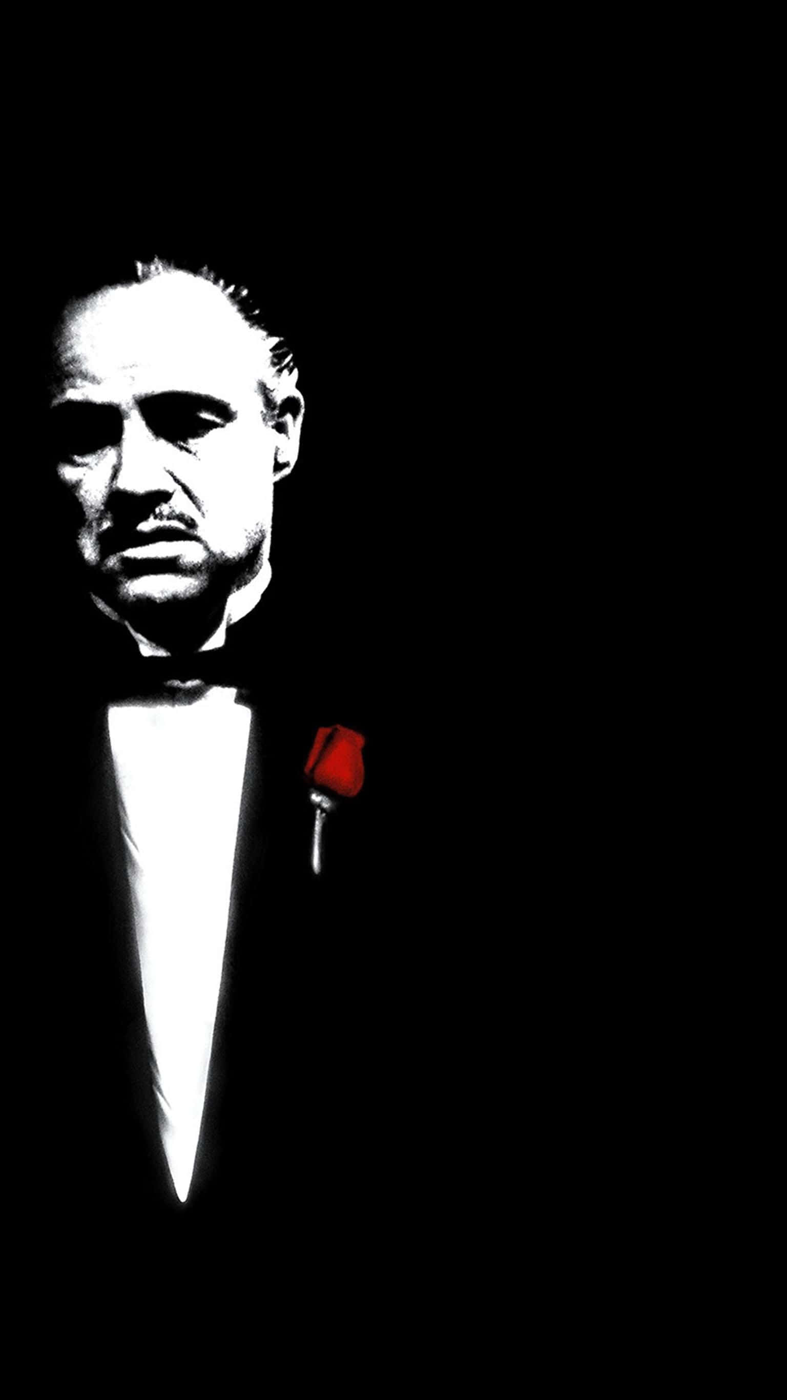 Mafia iPhone 桌布 壁紙 — 一張鮮明的黑白肖像，一名身穿燕尾服的男士在深色背景前，翻領上別著一朵紅玫瑰。
