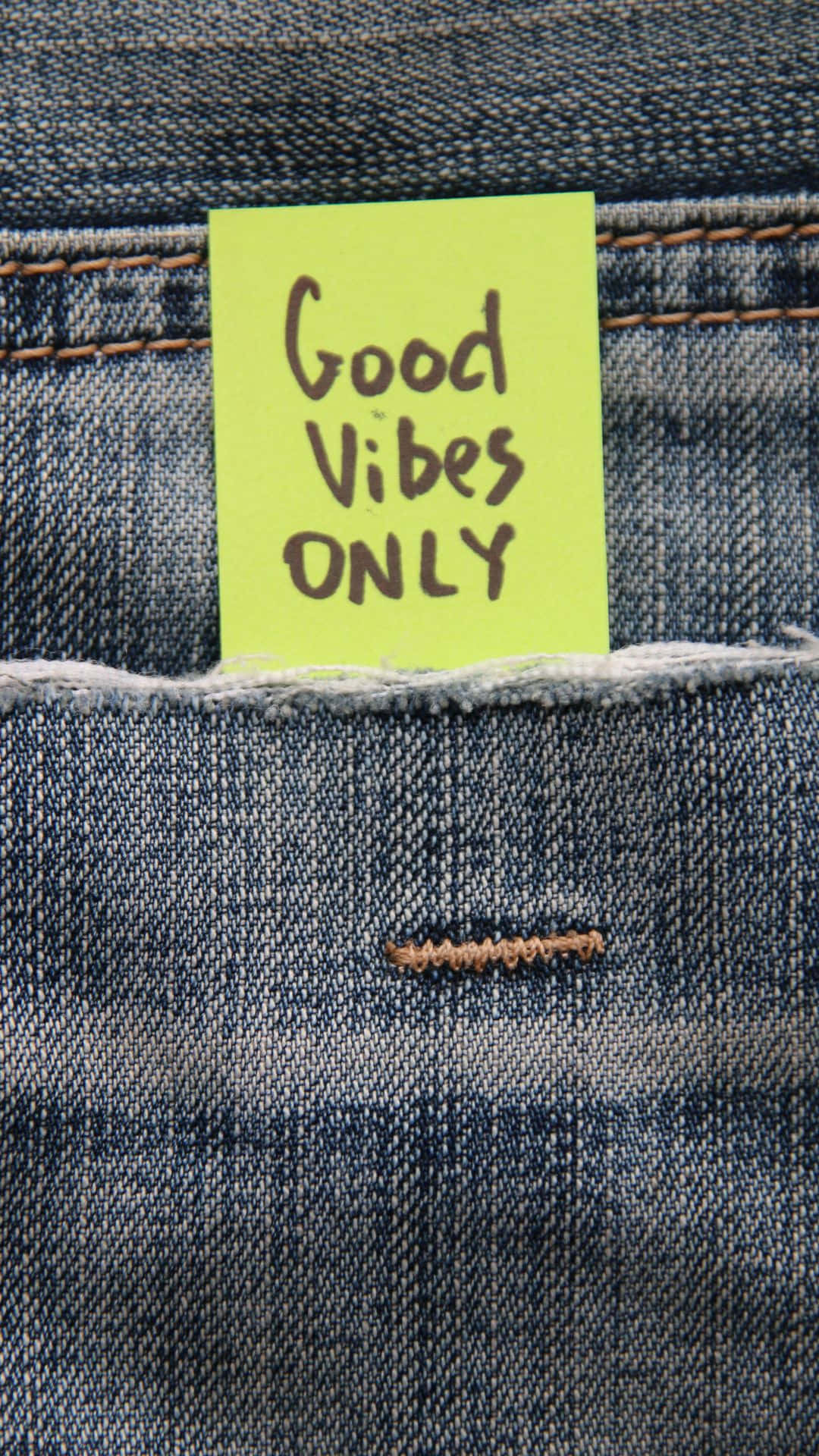 Denim 桌布 壁紙 — 一張鮮黃色便利貼，上面有手寫文字「Good Vibes ONLY」，塞在藍色牛仔褲的後口袋裡。