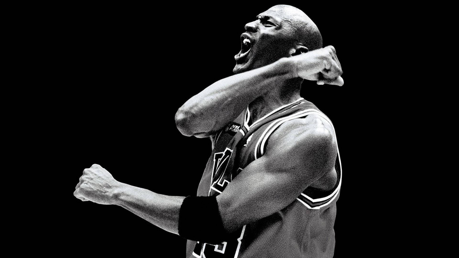 NBA 桌布 壁紙 — 一張麥可喬丹在黑暗背景下握緊拳頭、勝利咆哮的黑白照片。